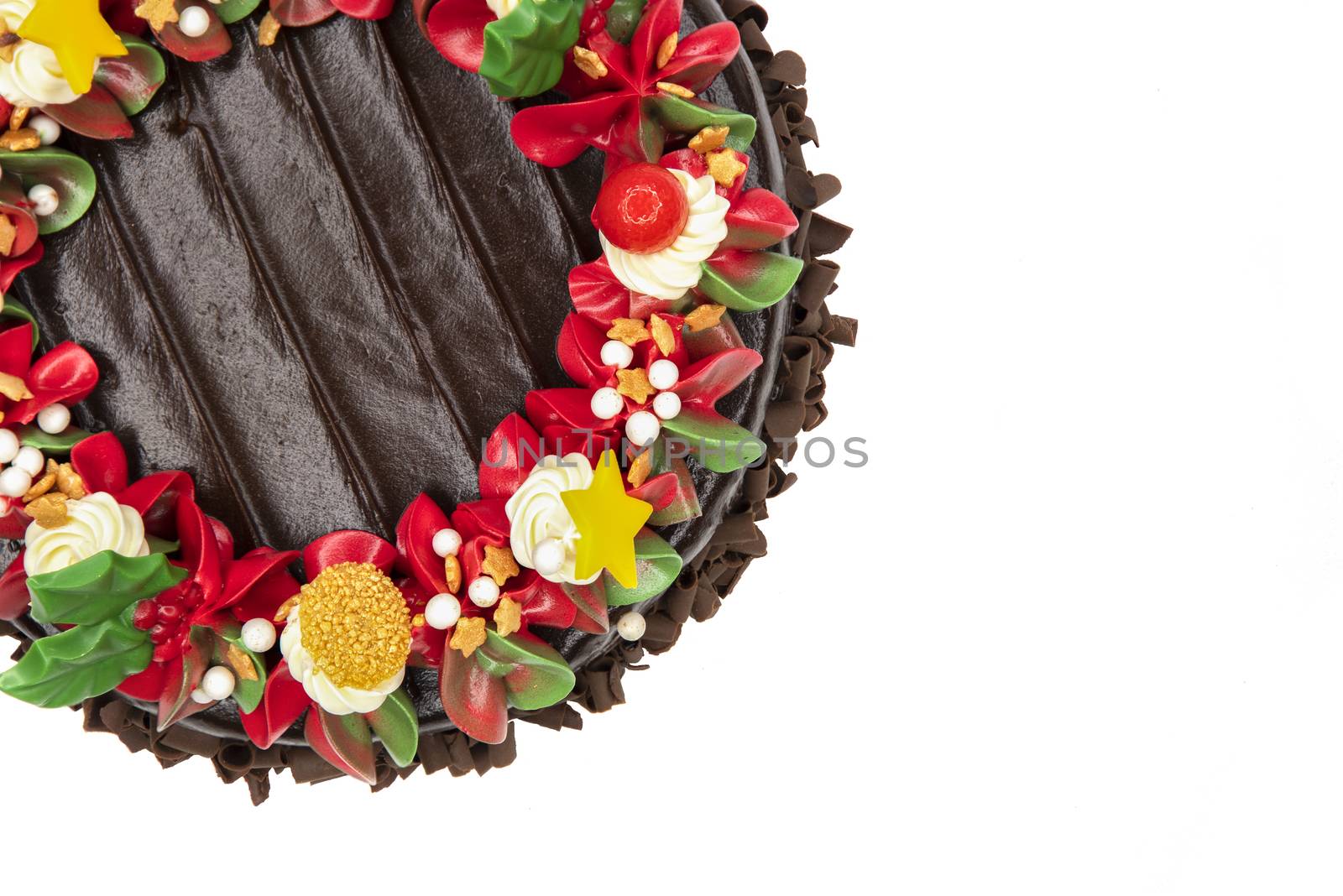 A chocolate cake decorated with red, white and green flowers and leaves, appropriate for Christmas and New Year celebration. Top view, closed up, isolated on white background with copy space.