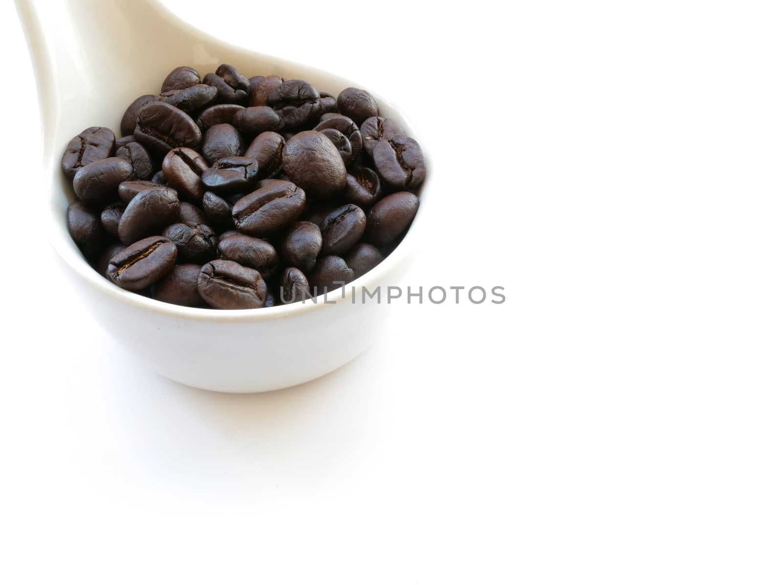 freshly roasted coffee beans in a ceramic spoon, isolated on white background
