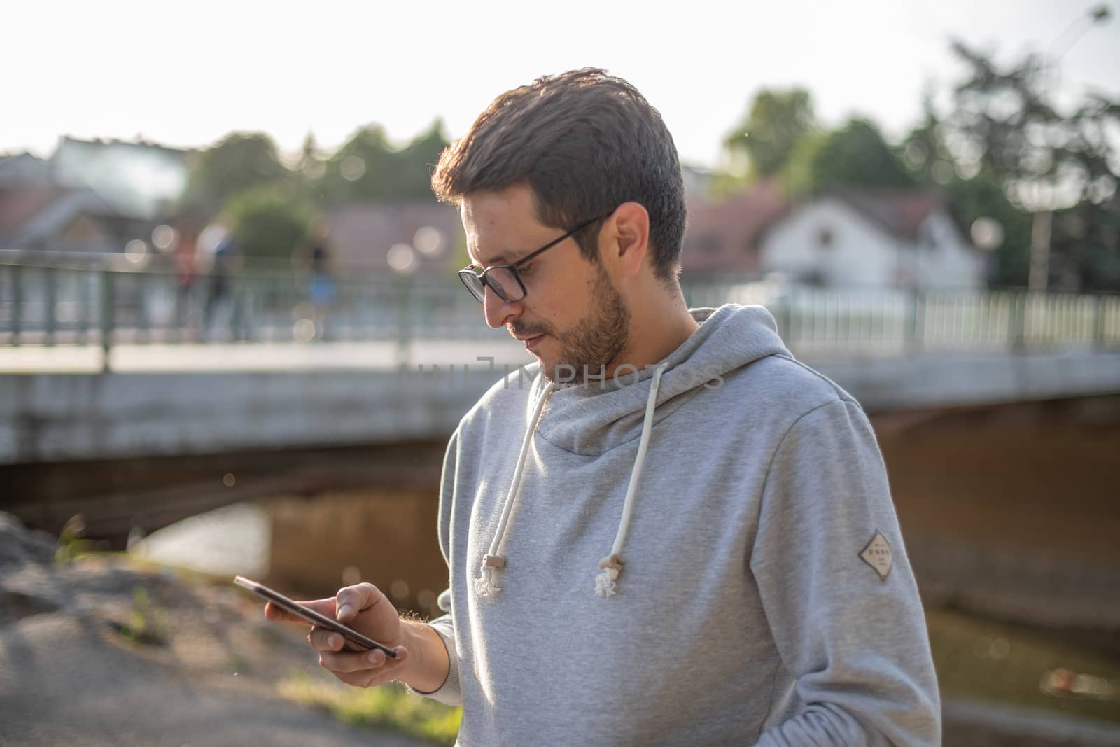 Man on smartphone in park, back light by adamr