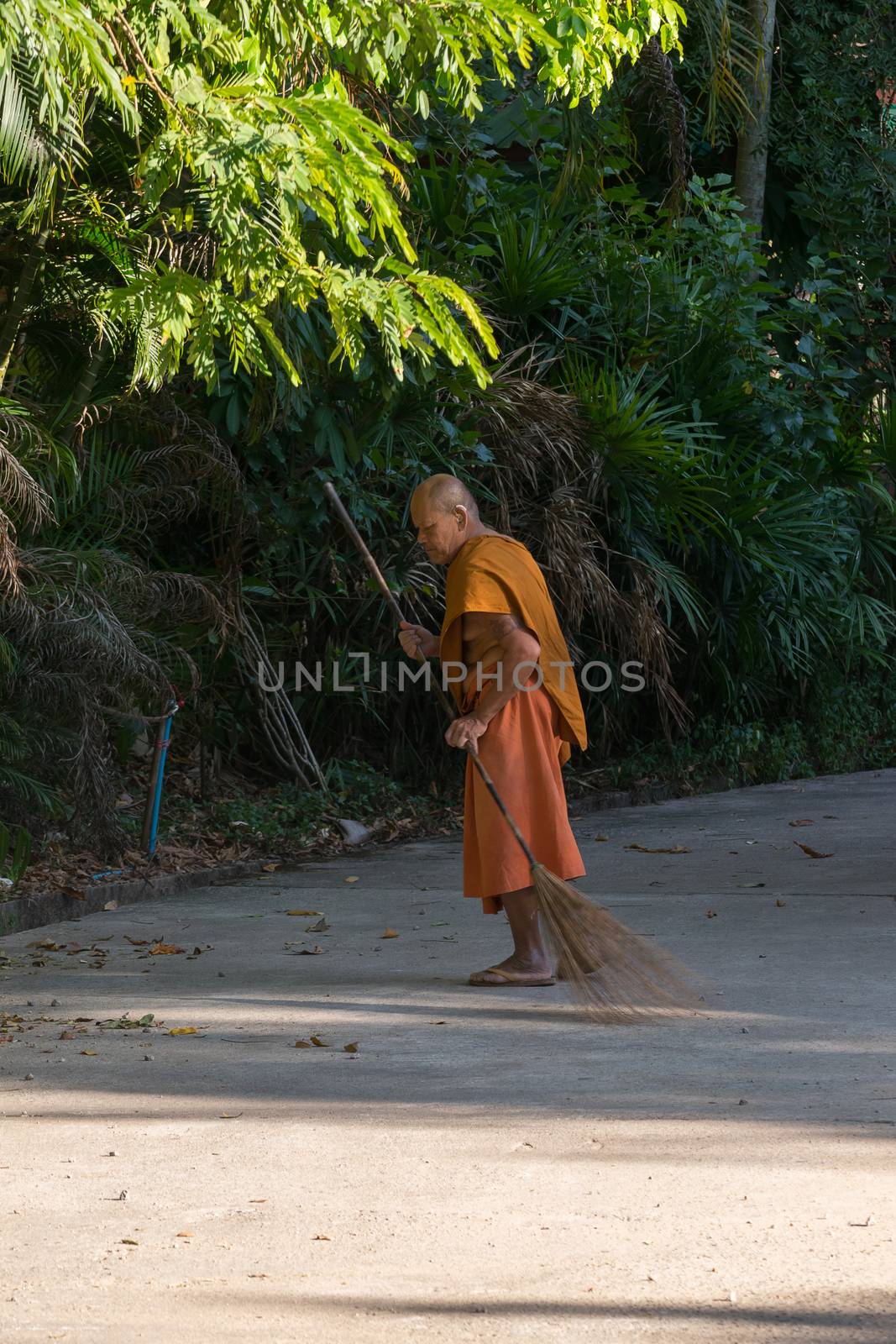 Chanthaburi, Thailand - February 1, 2016 : Thai monk sweeping a temple floor for clean at Thai forest temple (Wat Pa) in the Na Yai Am District of Chanthaburi, Thailand.