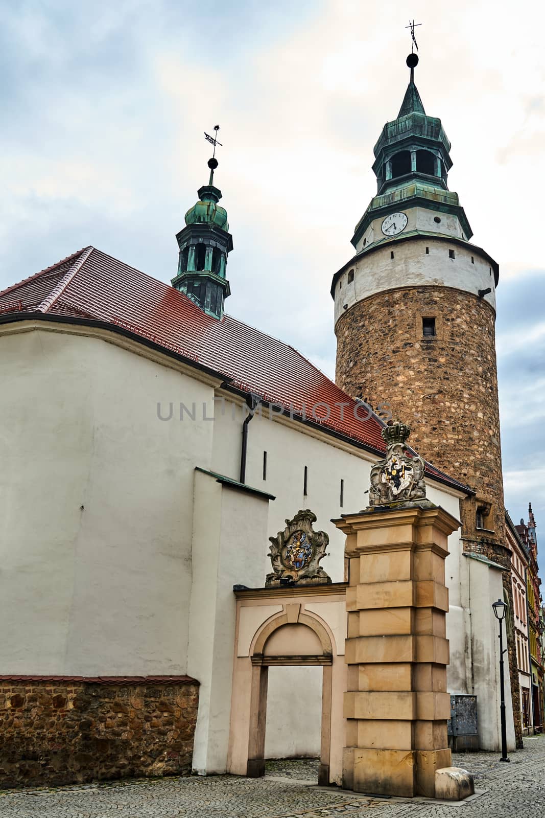 A medieval, stone church with a bell tower and a fragment of the city gate in Jelenia Gora in Poland