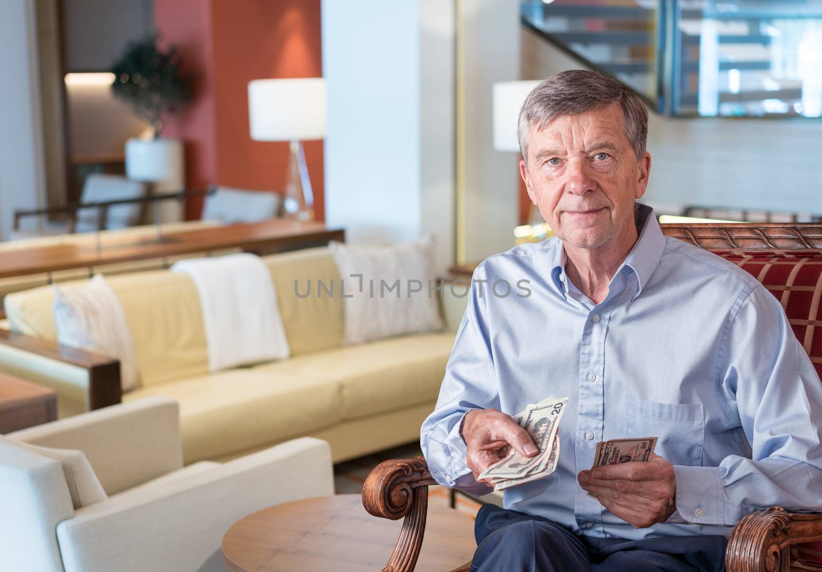 Senior man facing camera and holding US dollar bills as though handing to viewer by steheap