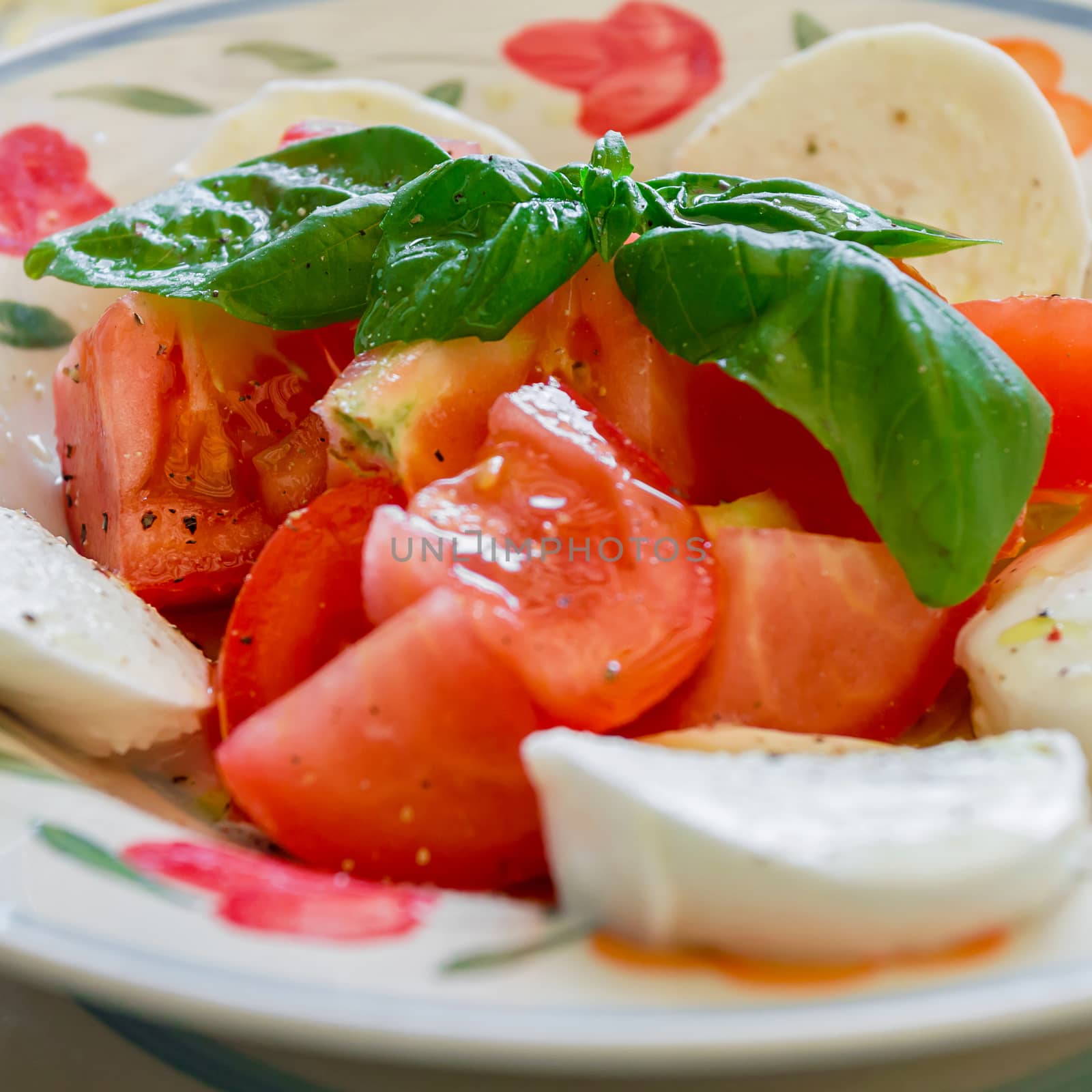 Caprese salad with mozzarella and tomatoes, closeup photo. Defocused blurry background.