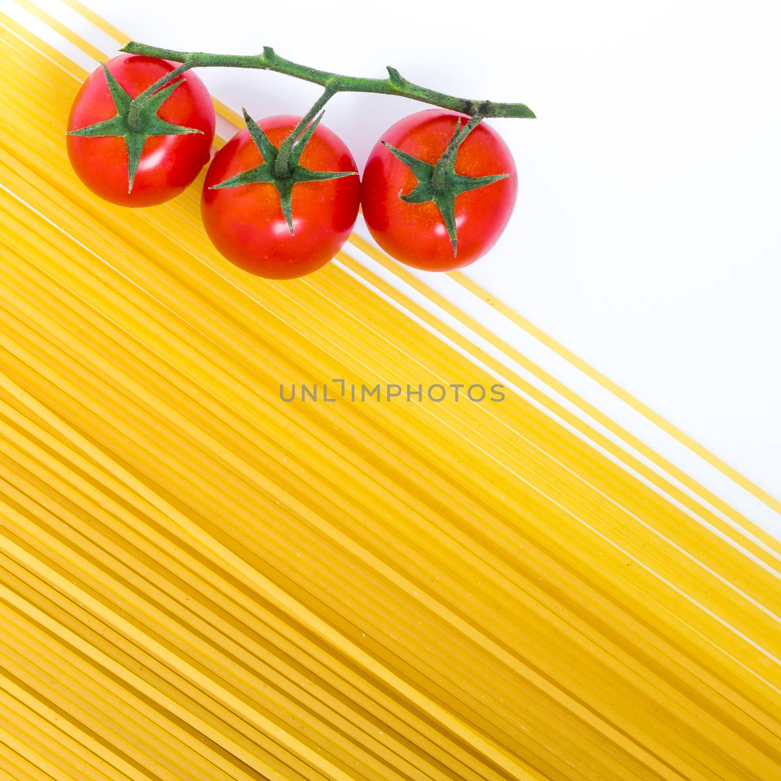 Spaghetti and cherry tomatoes isolated on white background. Uncooked Italian dried spaghetti. Top view. Flat lay.