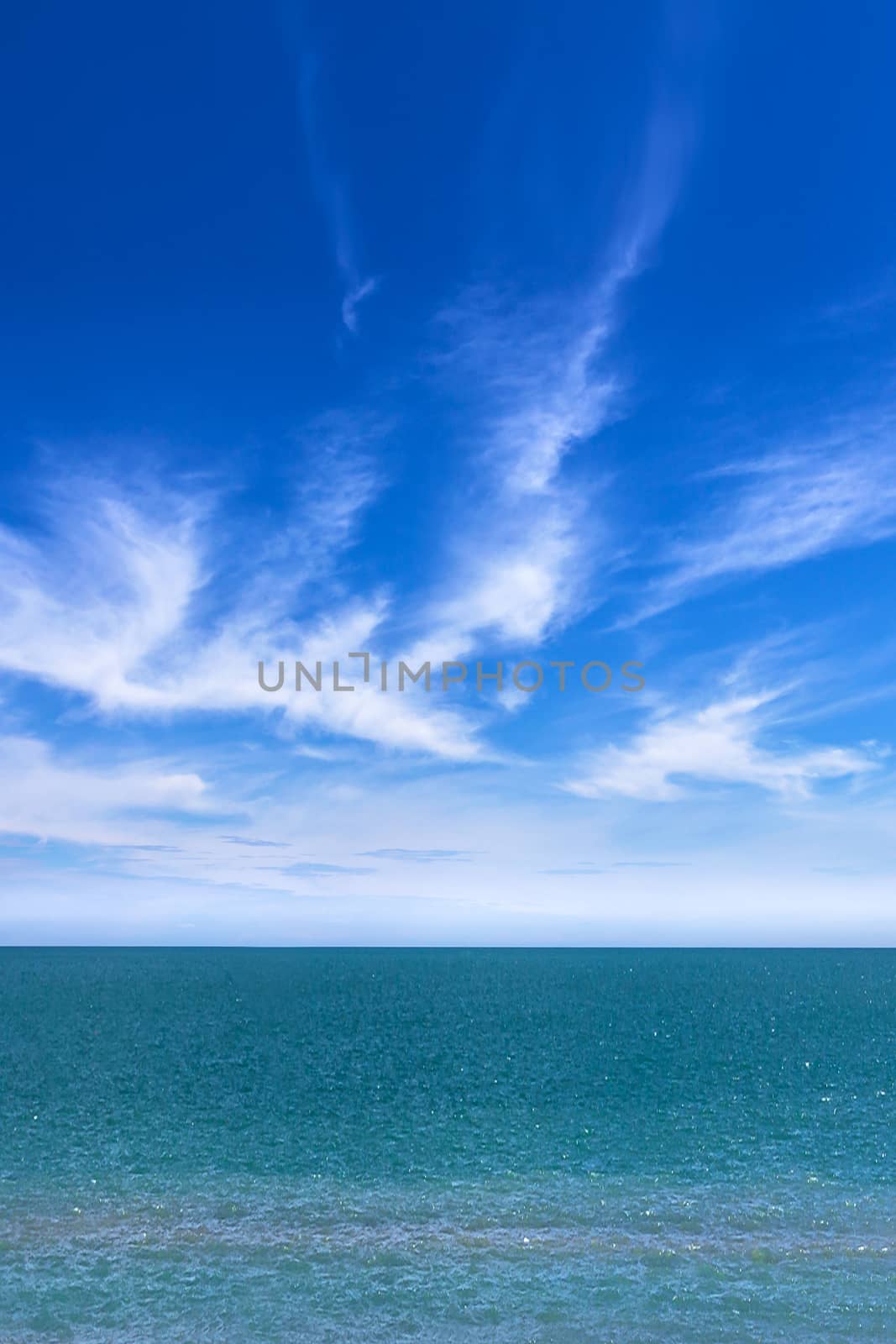 Vertical view of a amazing sea and blue sky with puffy clouds