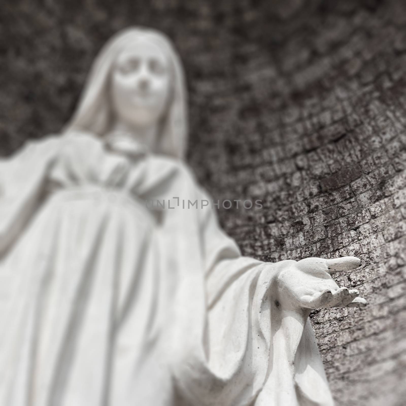 Blurred image Virgin mary statue background. Selected focus on her hand.