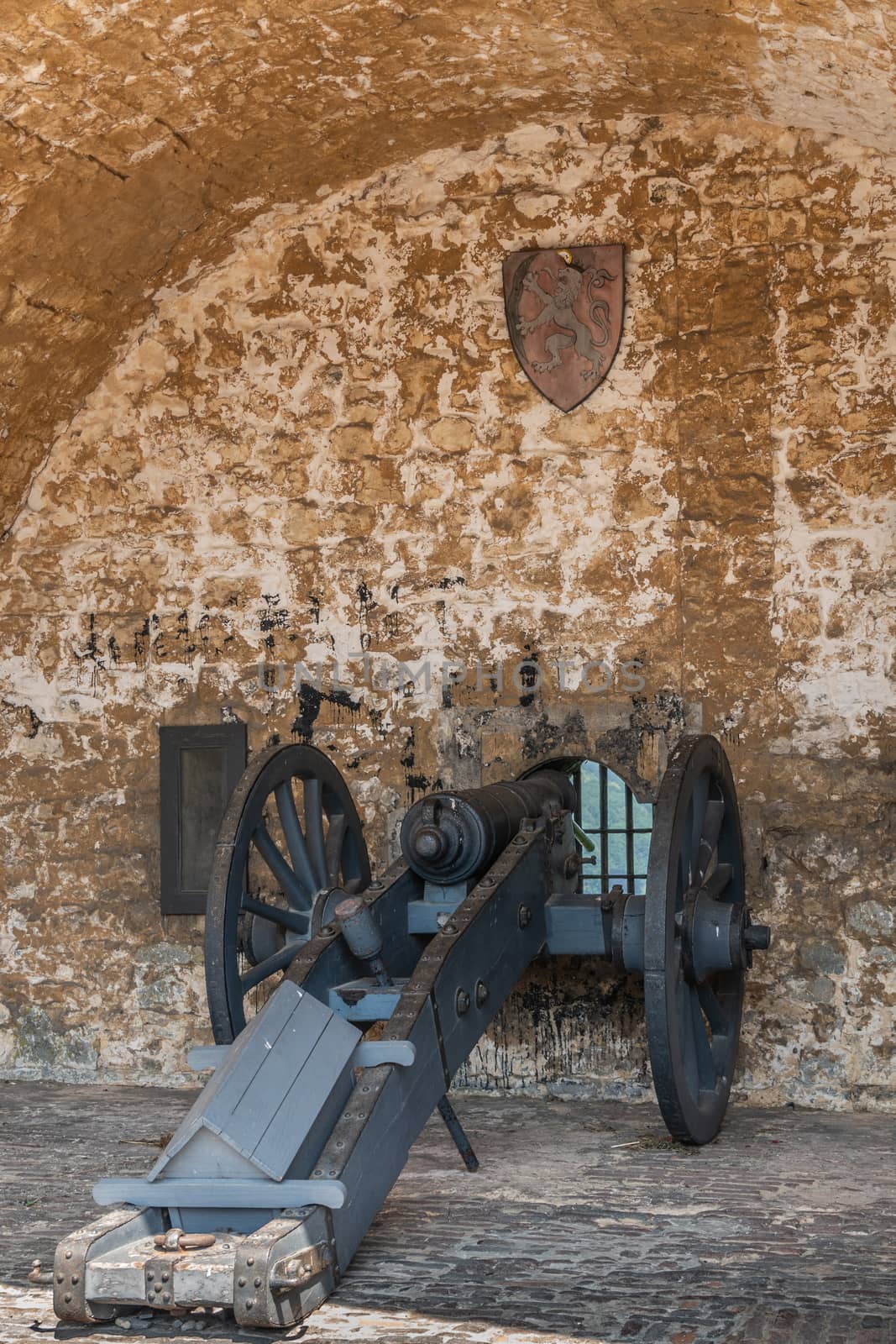Dinant, Belgium - June 26, 2019: Seen insde Citadelle.  Closeup of black cannon in beige stone niche aiming through window looking over north side of Meuse River.