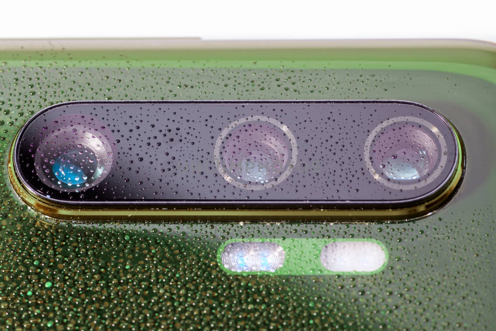 green phone camera lens covered with small water drops - close-up with selective focus and blur.