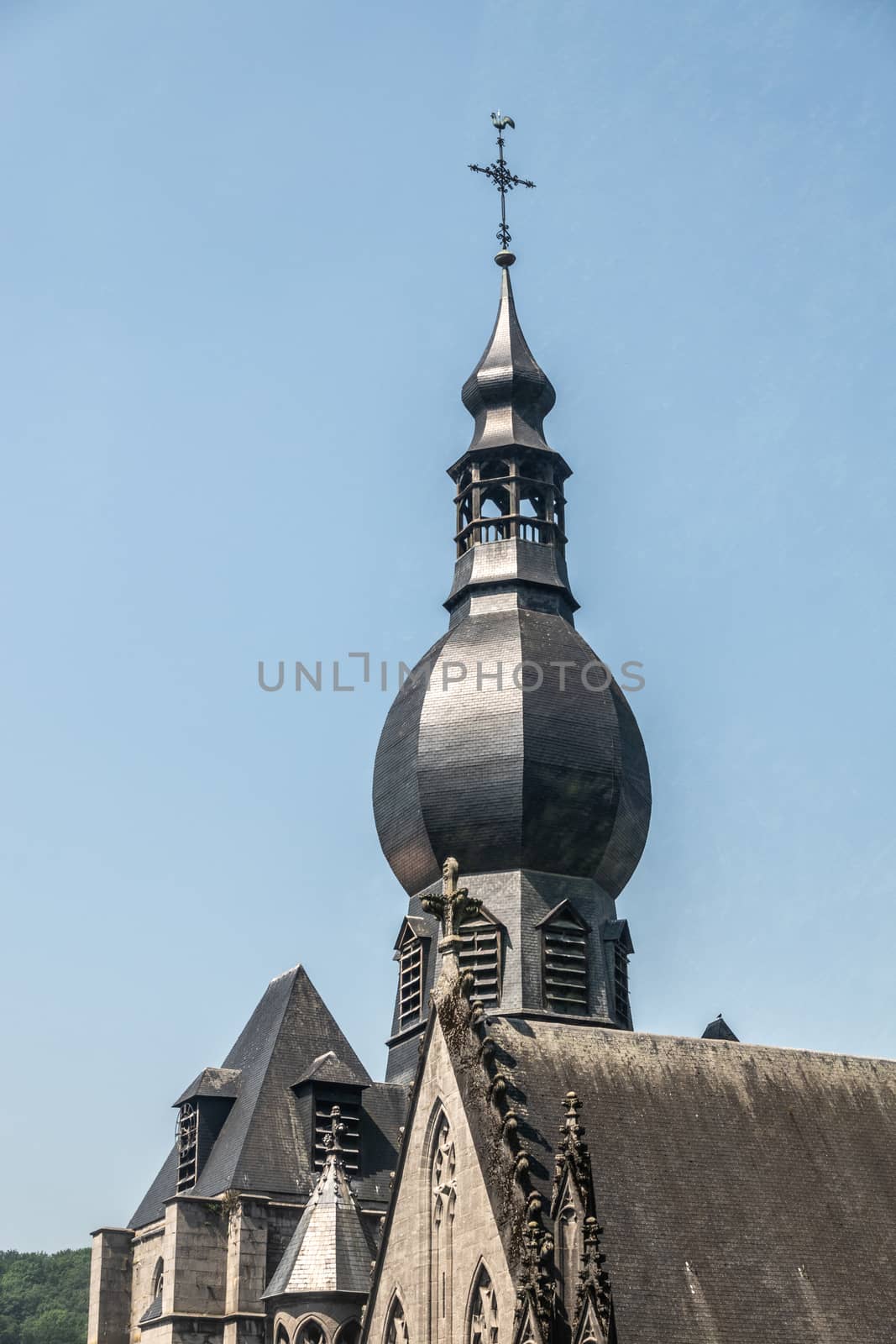 Dinant, Belgium - June 26, 2019: Black wiht shine Top of spire of Notre Dame Church against blue sky.