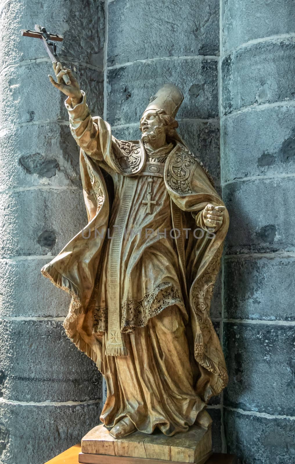 Dinant, Belgium - June 26, 2019: Inside Collégiale Notre Dame de Dinant Church. Gold painted stone statue of Belgian medieval Saint Perpėte against pillar.