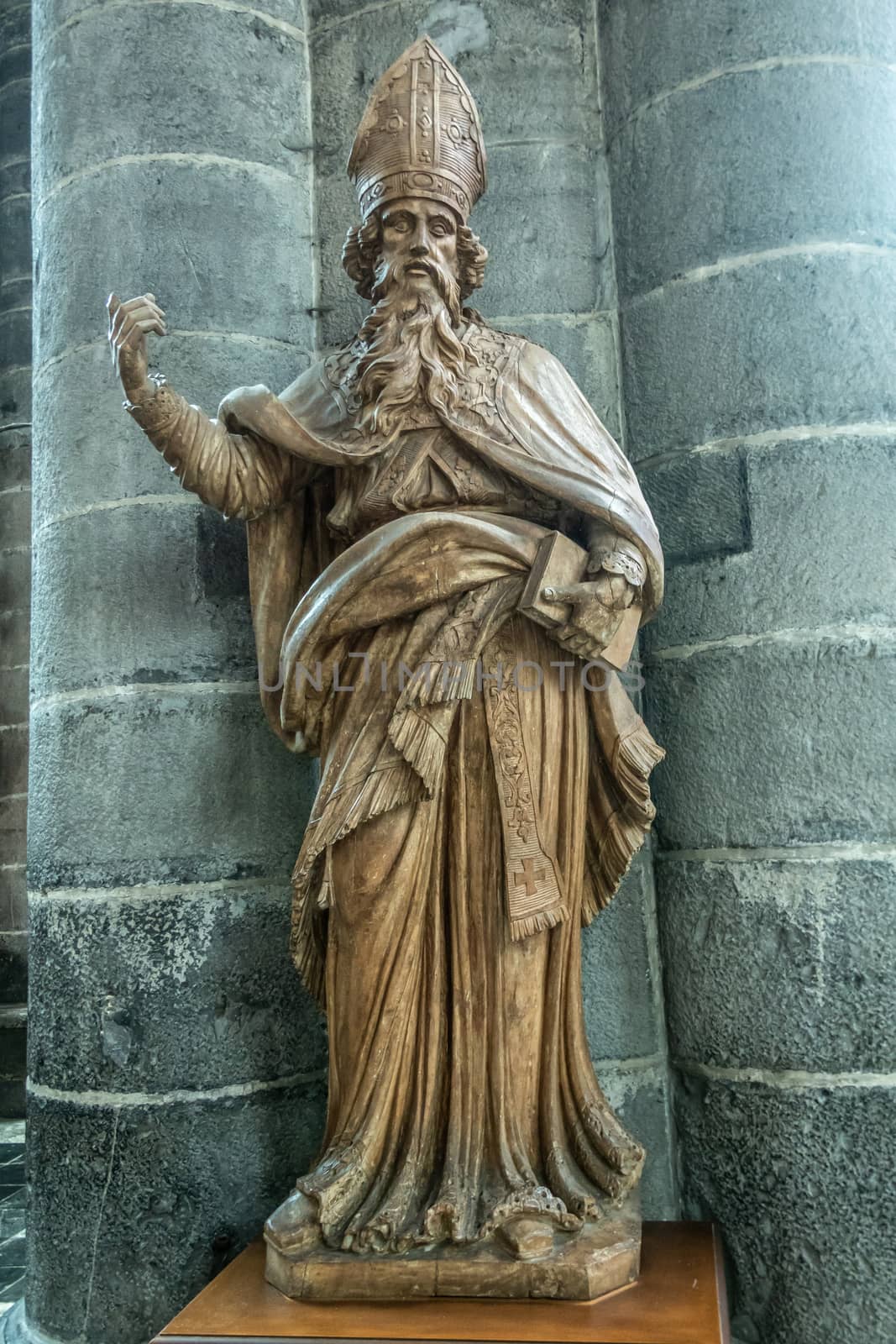Dinant, Belgium - June 26, 2019: Inside Collégiale Notre Dame de Dinant Church. Brown painted stone statue of Belgian medieval Saint Hubert against pillar..