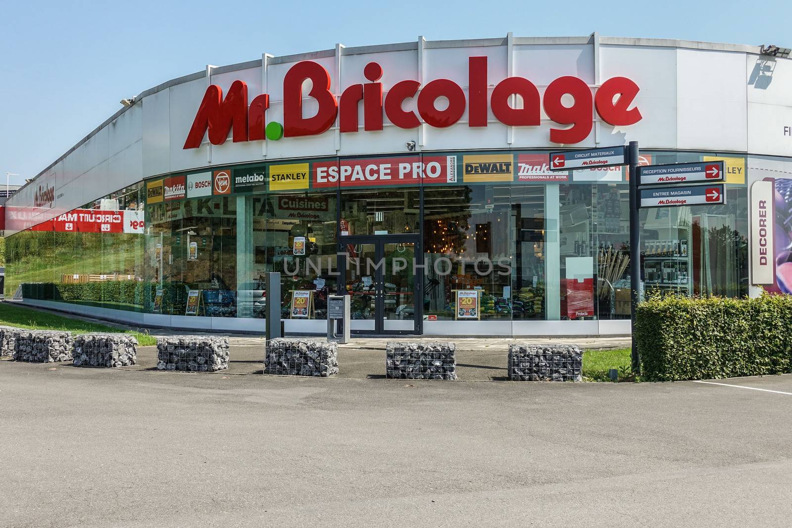 Dinant, Belgium - June 26, 2019: Mr. Bricolage red-on-white home repair, building and garden center has facade of display windows under blue sky.