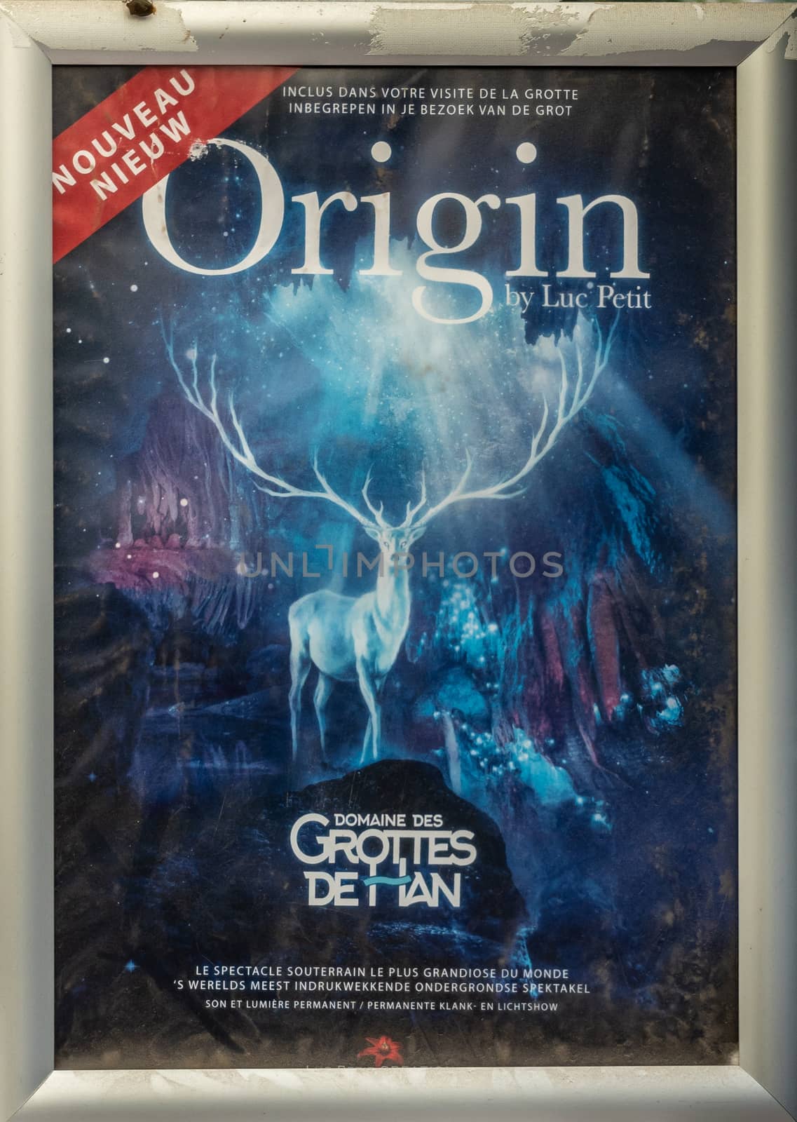 Han-sur-Lesse, Belgium - June 25, 2019: Grottes de Han poster and French and Dutch text. blue dominant, large deer in center, caves in back.