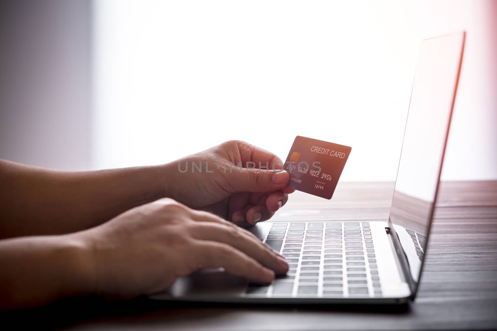 hand holding credit card over laptop computer, online shopping concept