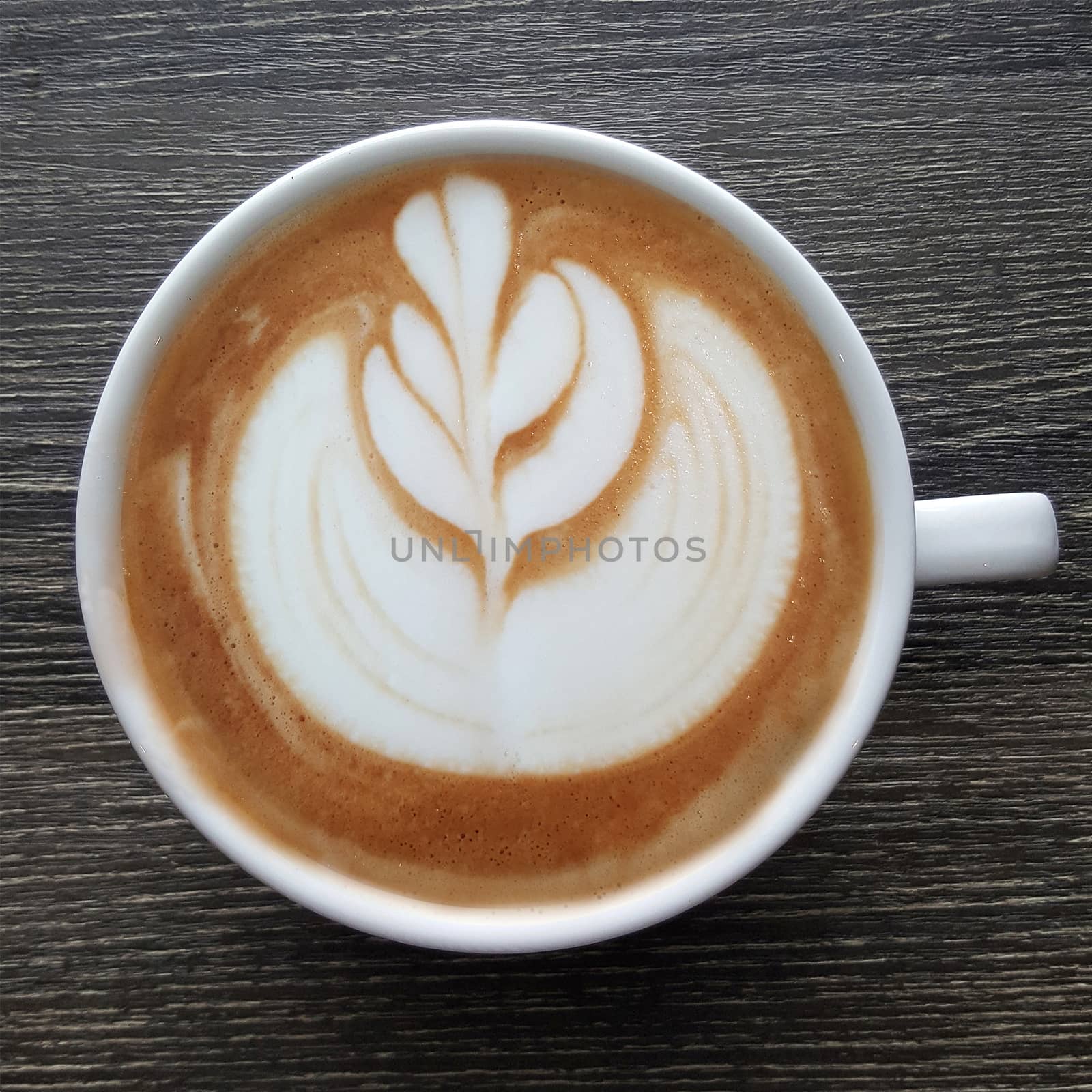 Top view of a mug of latte art coffee on timber background.