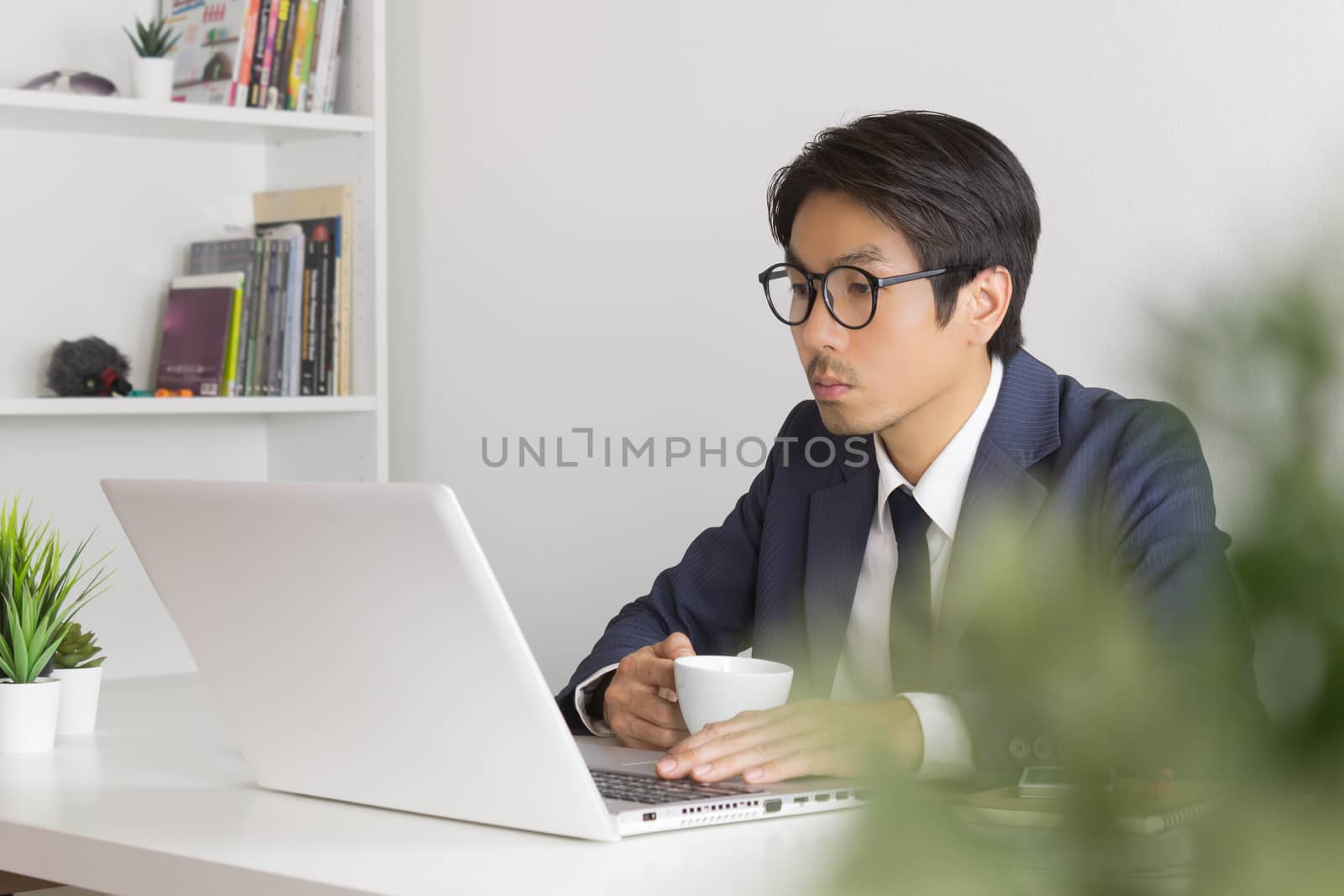 Asian Businessman Wear Eyeglasses Seriously Analyze Financial Data in Laptop. Asian businessman working in office