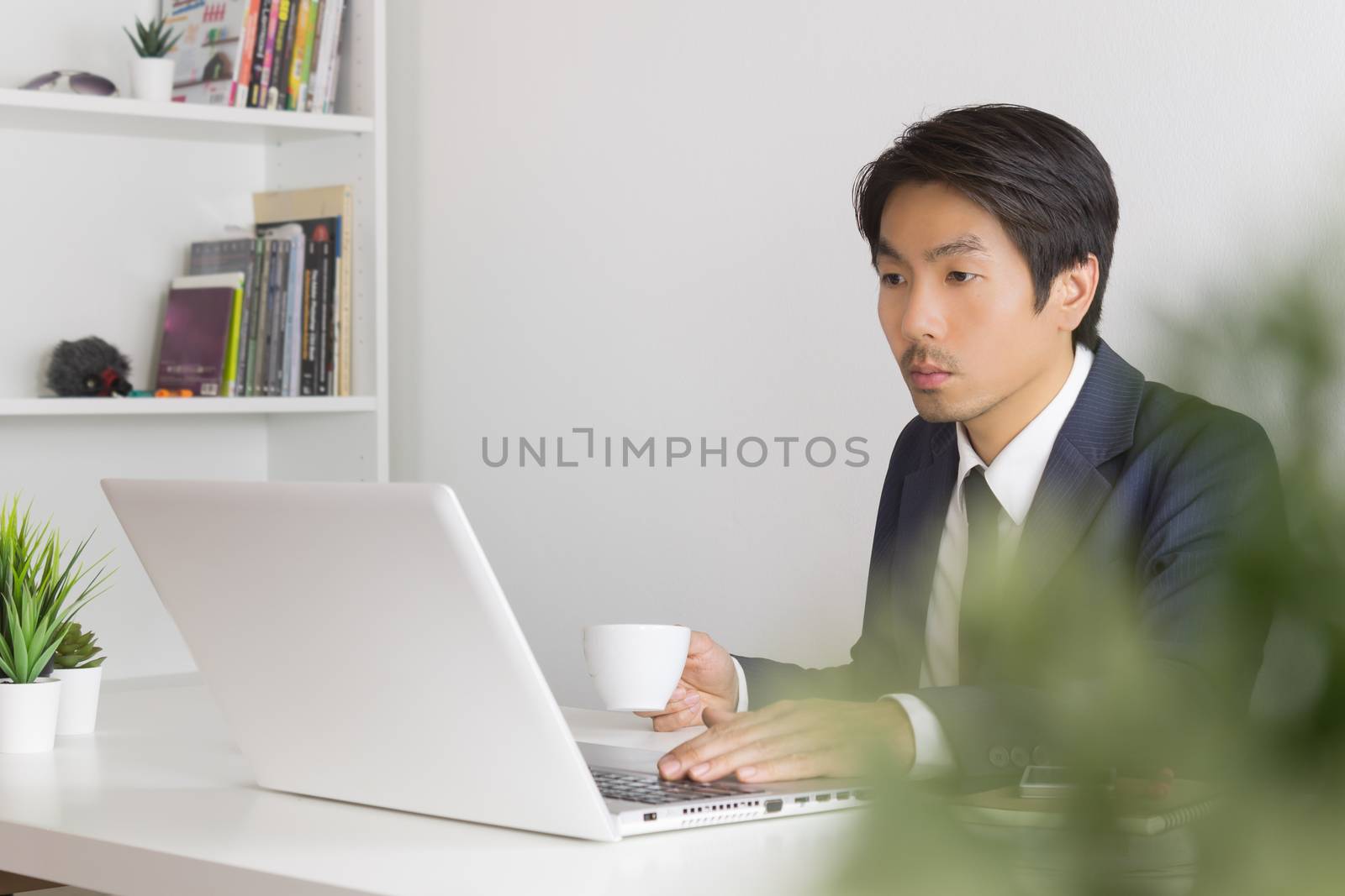 Asian Businessman with White Coffee Cup in Break Time with Tree Foreground in Office. Relax time for Asian businessman