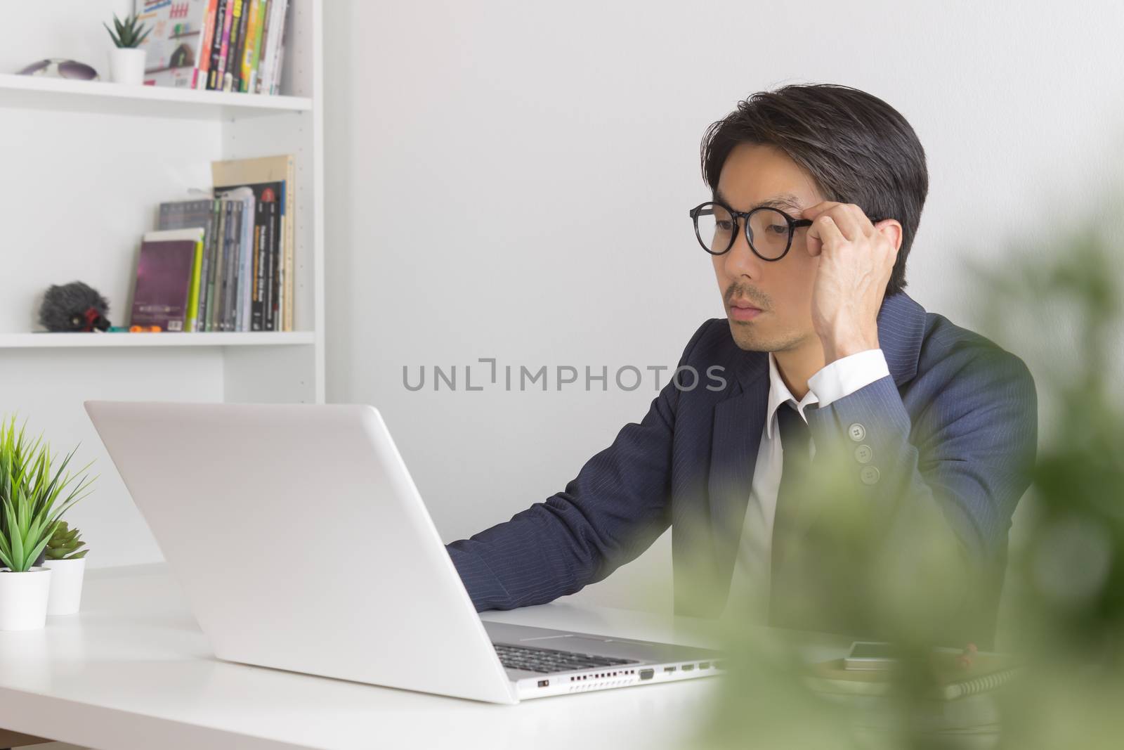 Asian Financial Advisor or Asian Consulting Businessman Analyze Financial Data in front of Laptop. Asian financial advisor or Asian consulting businessman working in office