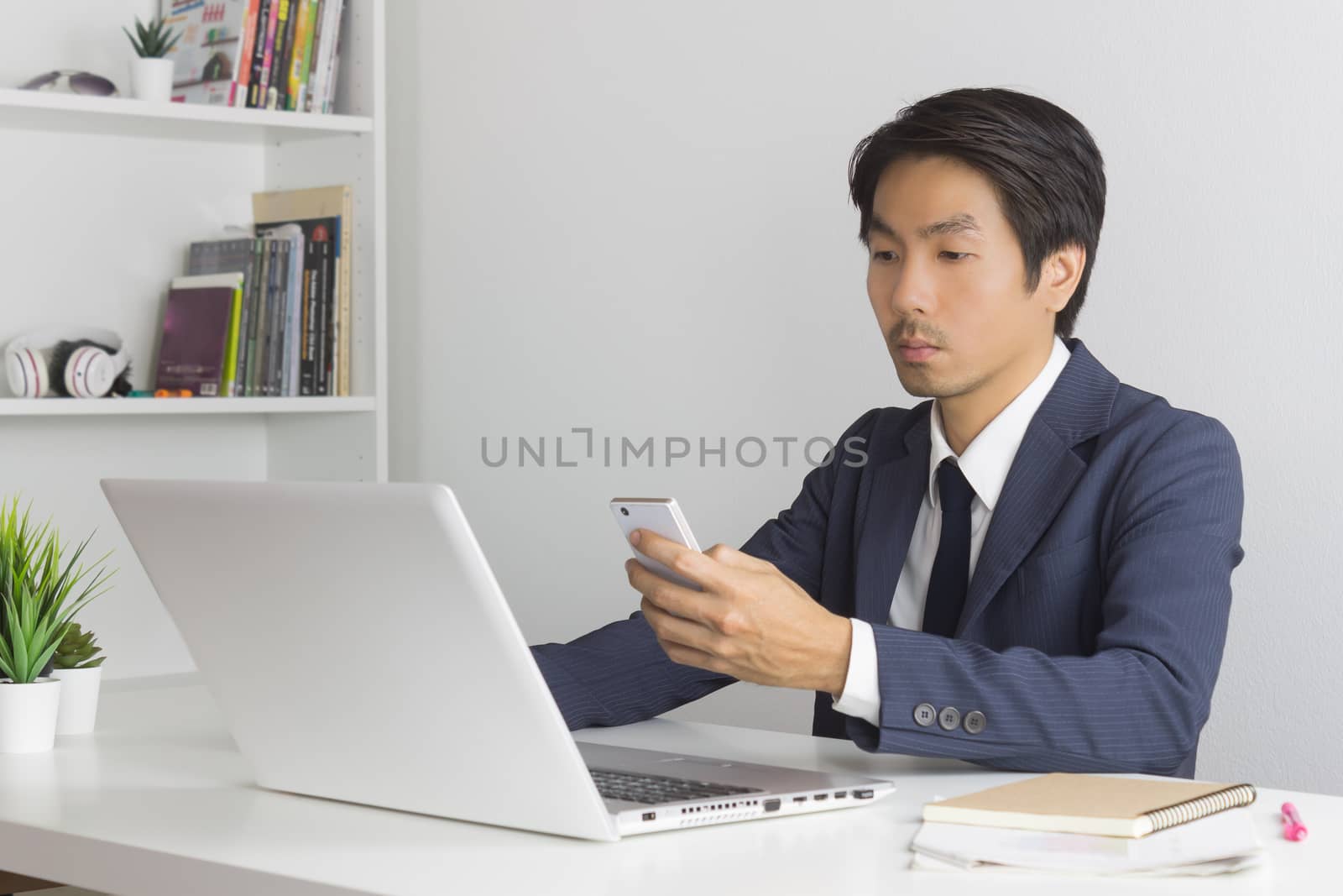 Asian Financial Advisor or Asian Consulting Businessman Contact with Customer by use Smartphone and Laptop in office. Asian Financial Advisor or Asian Consulting Businessman chat and send message with customer