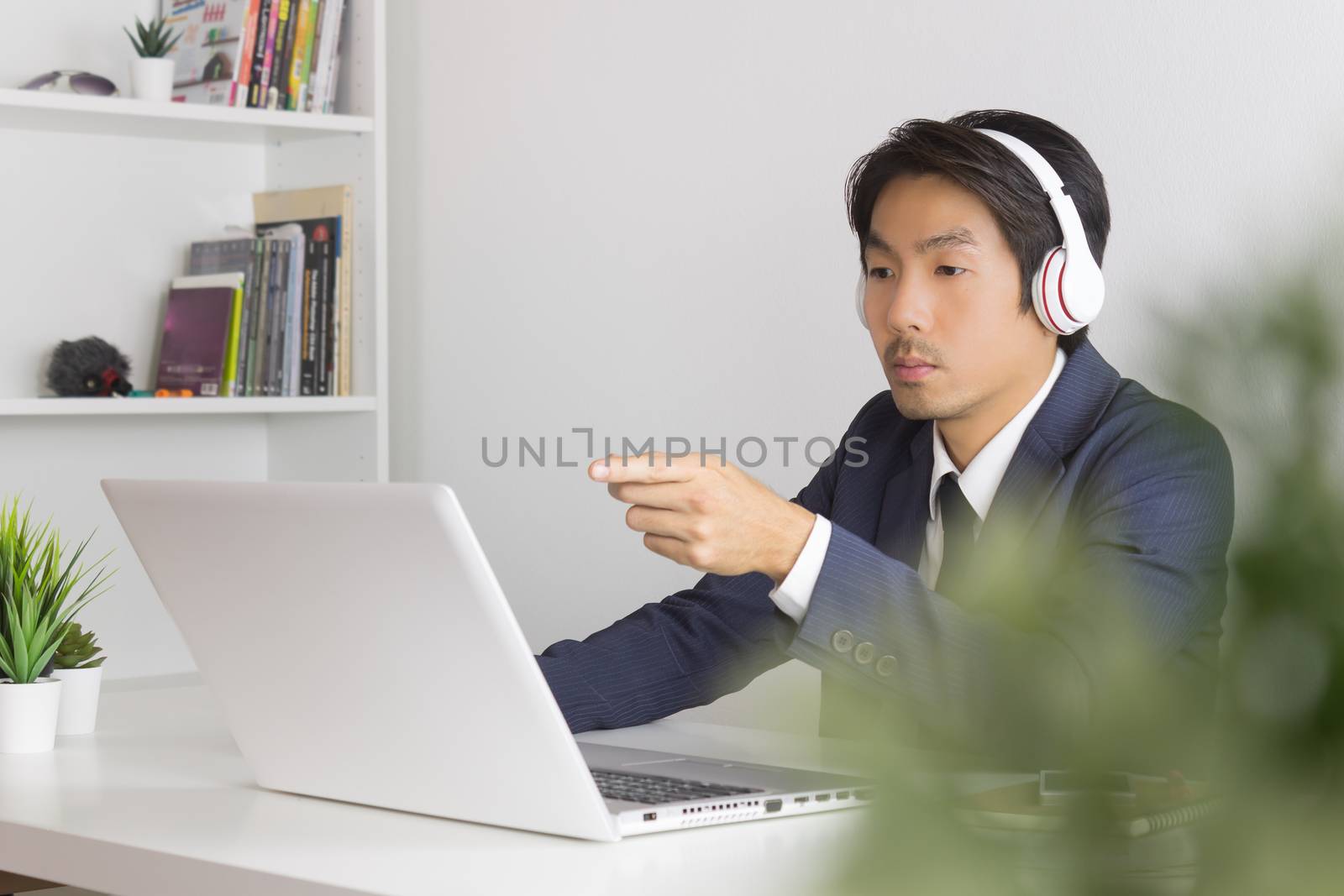 Asian Man Call Center in Suit Wear Headset Seriously Answer Customer Questions. Asian man call center working in front of laptop