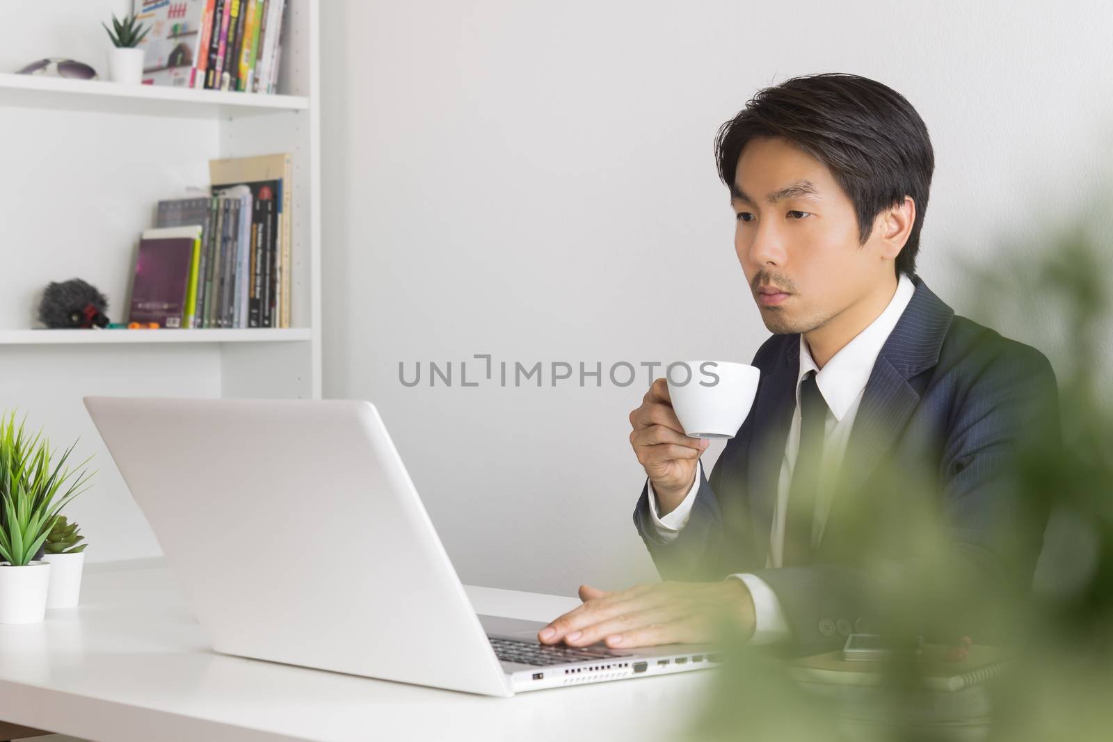 Asian Businessman Drink a Cup of Coffee in Break Time with Tree Foreground in Office. Relax time for Asian businessman