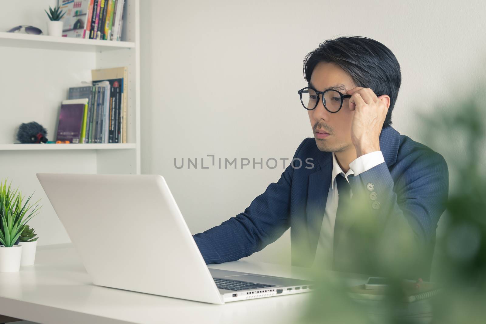 Asian Financial Advisor or Asian Consulting Businessman Analyze Financial Data in front of Laptop. Asian financial advisor or Asian consulting businessman working in office