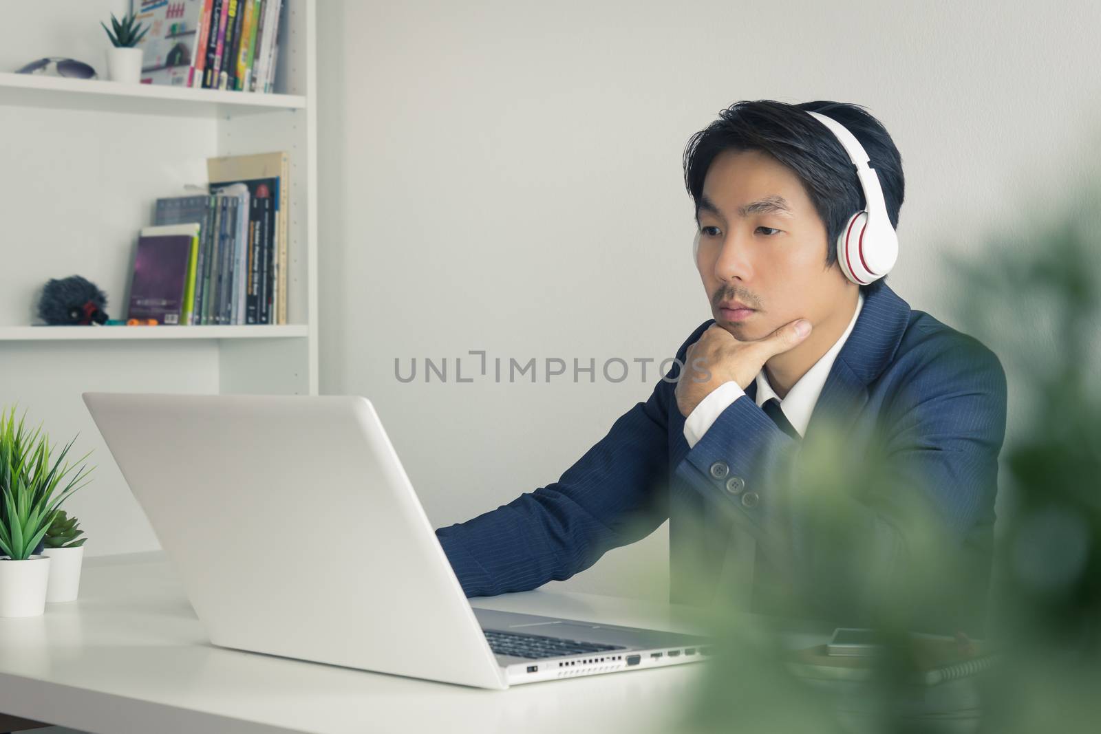 Asian Financial Advisor or Asian Consulting Businessman Seriously Analyze Financial Data in front of Laptop. Asian financial advisor or Asian consulting businessman contact with customer via internet