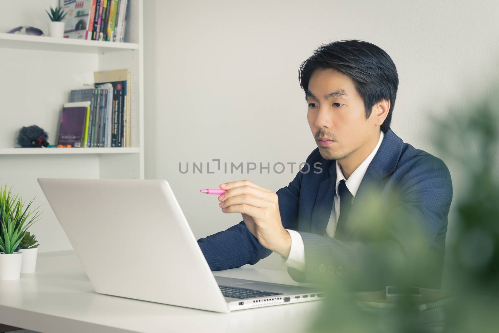 Asian Financial Advisor or Asian Consulting Businessman Seriously Customer Recommend in front of Laptop. Asian financial advisor or Asian consulting businessman contact with customer via internet