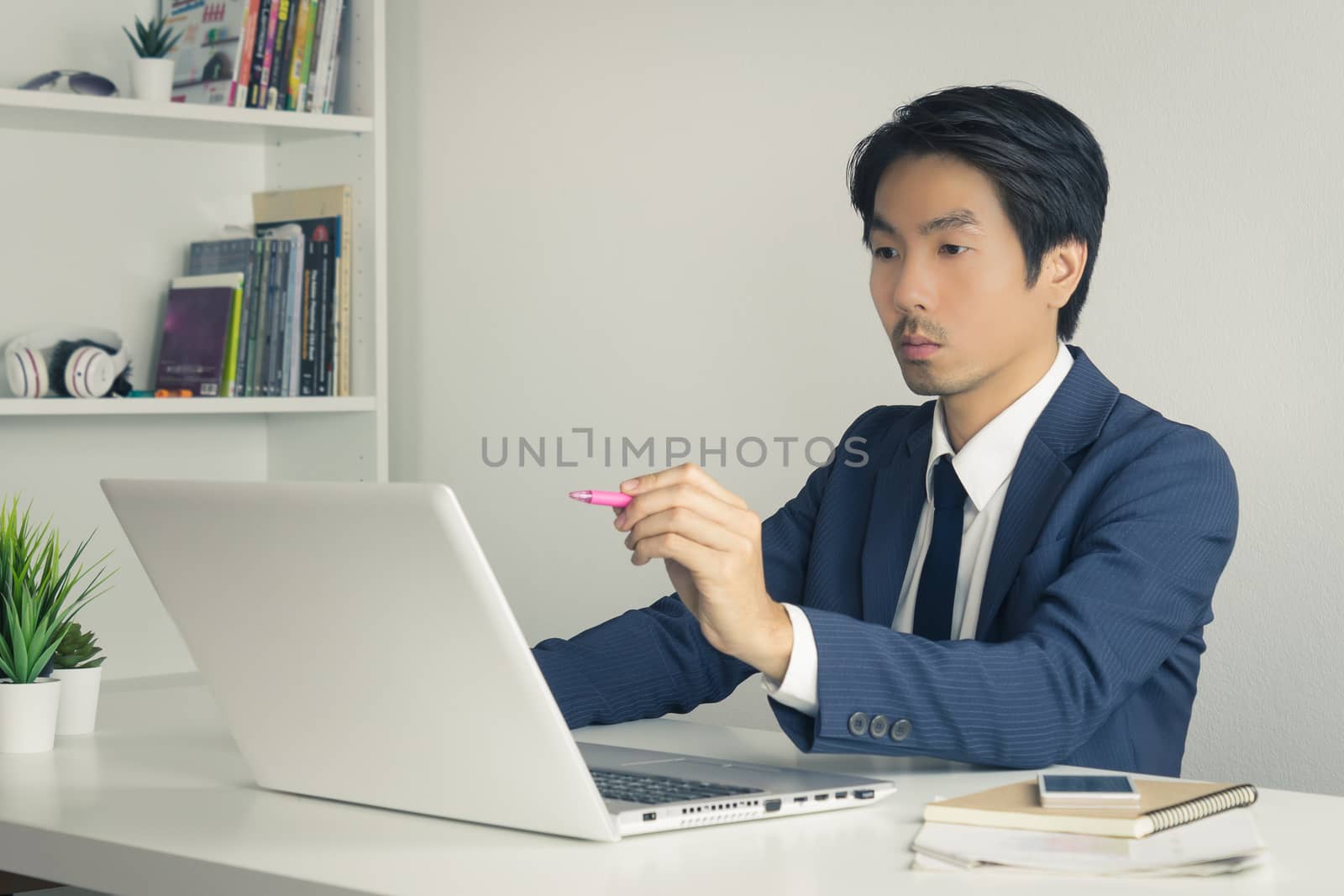 Asian Financial Advisor or Asian Consulting Businessman in Suit Suggest Customer Via Internet. Asian Financial Advisor or Asian Consulting Businessman working in office