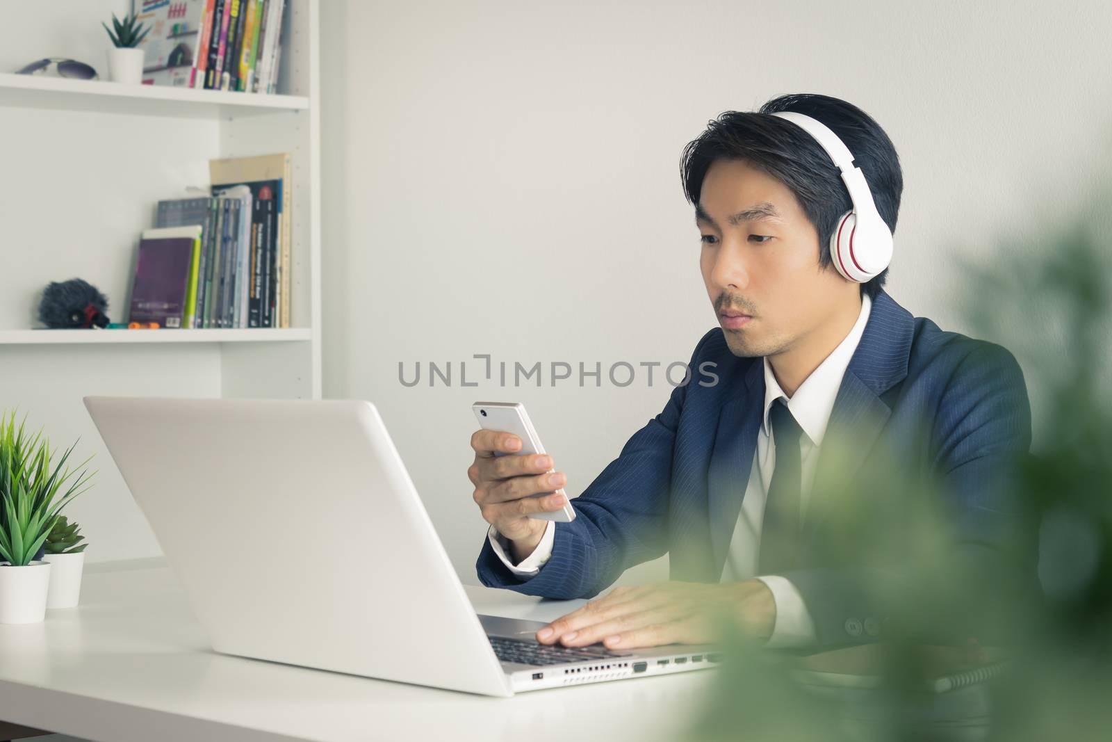 Asian Man Call Center Contact with Customer by Smartphone and Laptop. Asian man call center answers the customer question in front of laptop in office