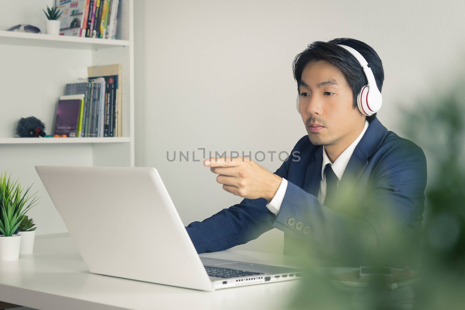 Asian Man Call Center in Suit Wear Headset Seriously Answer Customer Questions. Asian man call center working in front of laptop
