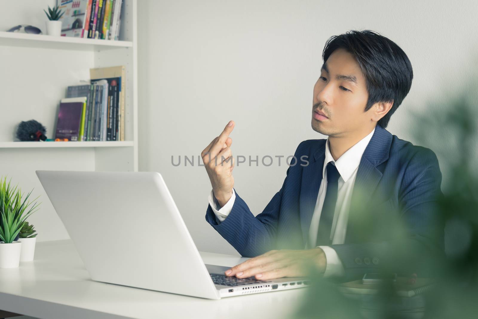 Angry Asian Businessman Show Middle Finger in front of Laptop in by steafpong