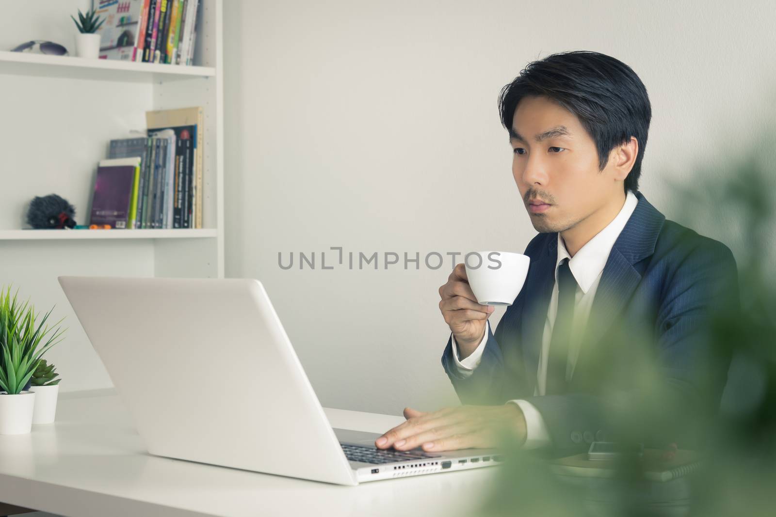 Asian Businessman Drink a Cup of Coffee in Break Time with Tree Foreground in Office. Relax time for Asian businessman