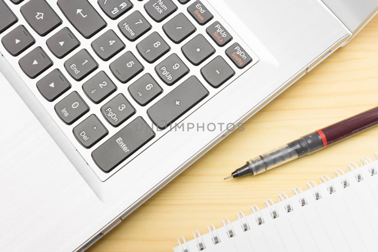 Silver laptop and notebook and pen on wood table. Business concept background