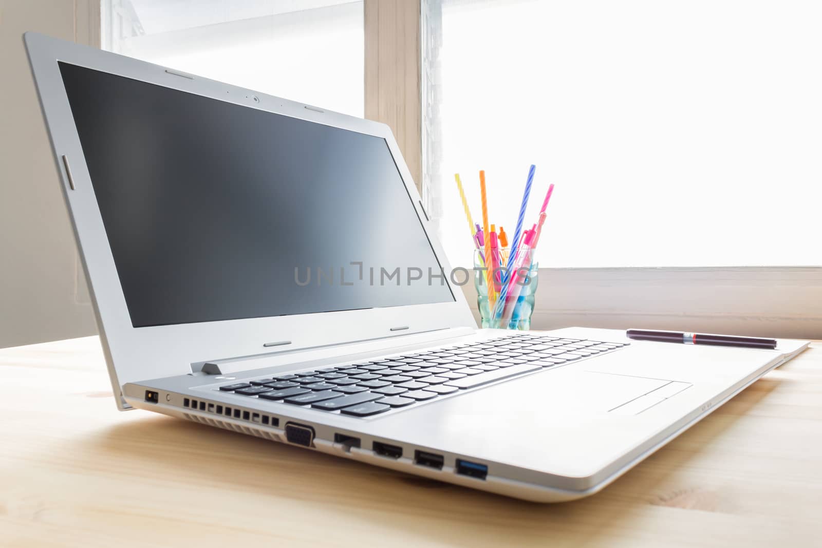 Laptop and notebook and pen and glass on wood table in old office with soft evening light