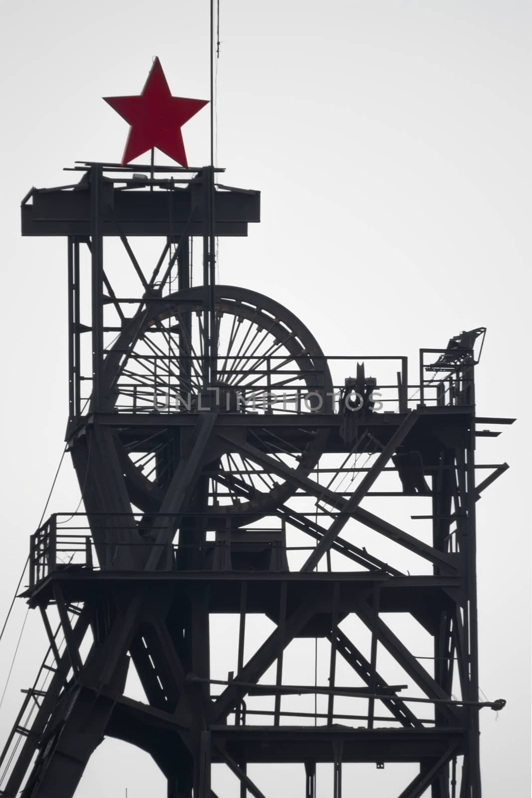 silhouette colliery coal mine with wheels and soviet star against the sky by jk3030