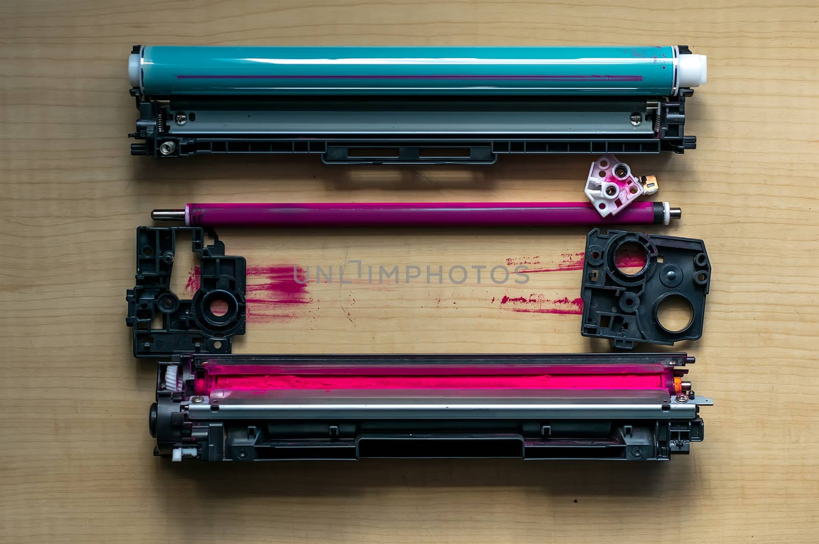 Disassembled into parts of the color cartridge from the laser printer is on a wooden table