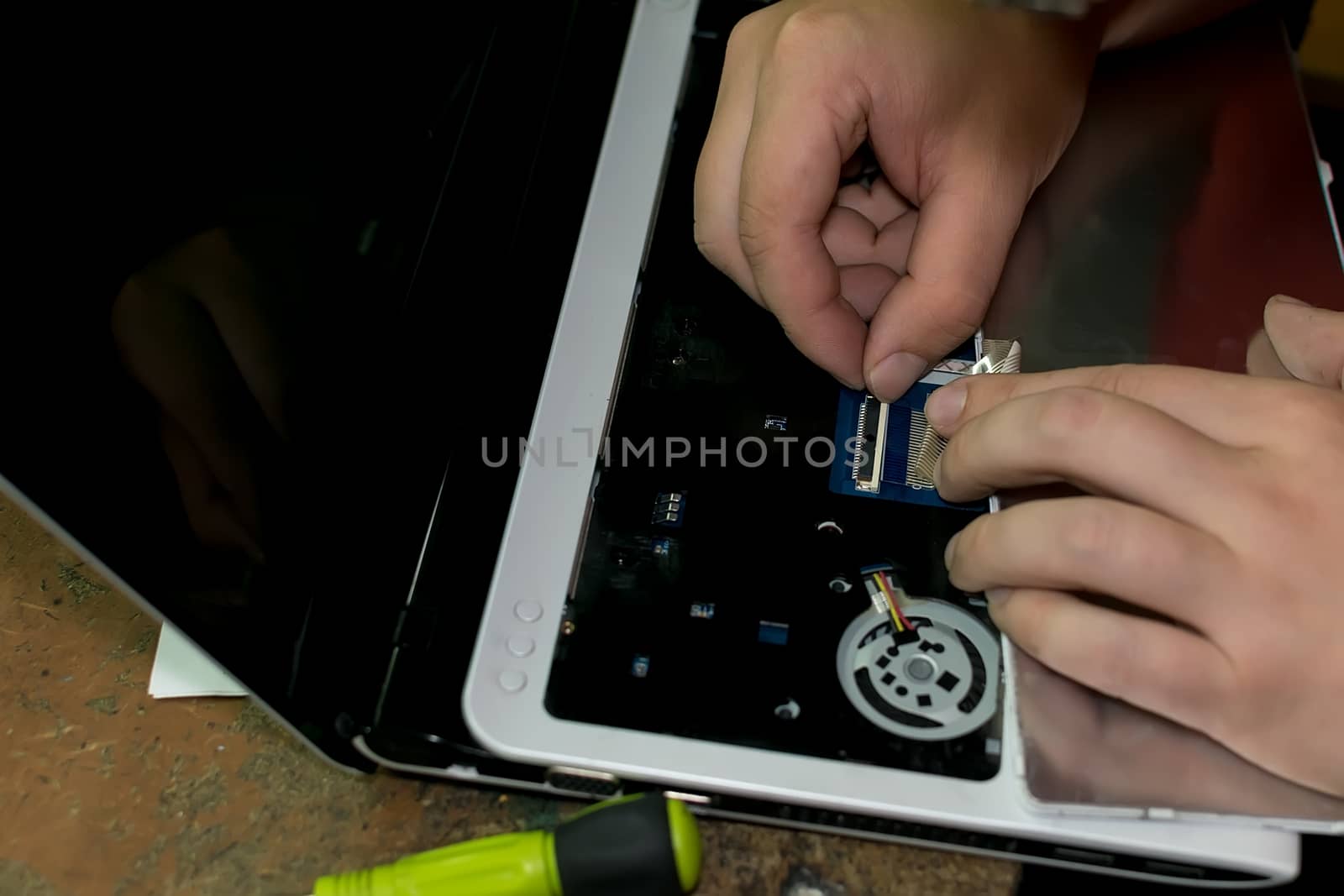 the hands of a man repairing a laptop by jk3030