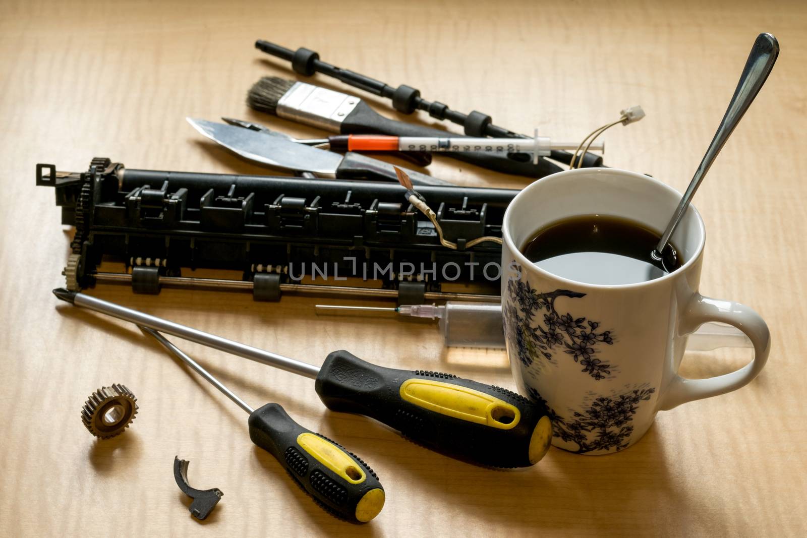 printer parts, tools, grease, broken gear and coffee mug on the table by jk3030