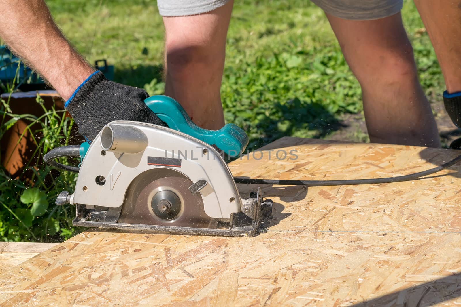 a man sawing a Board with a power tool, chips fly in all directions. Construction, wood processing by jk3030