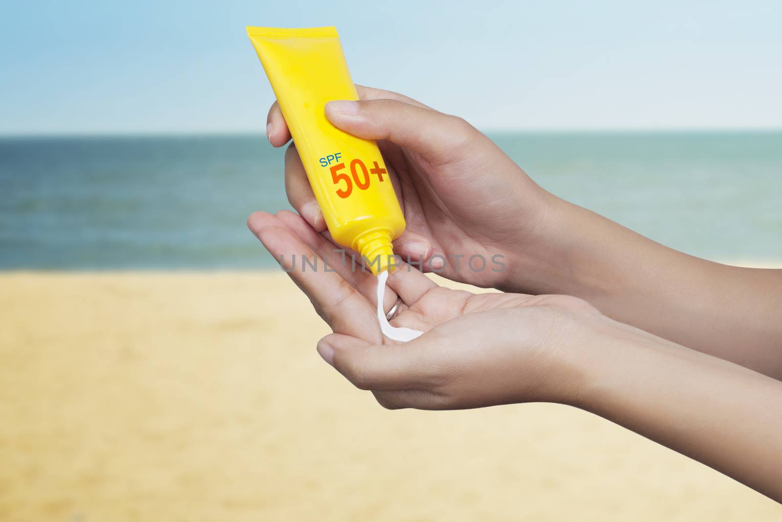 woman applying sunscreen on her hand with sea background. SPF sunblock protection concept. Travel vacation by asiandelight