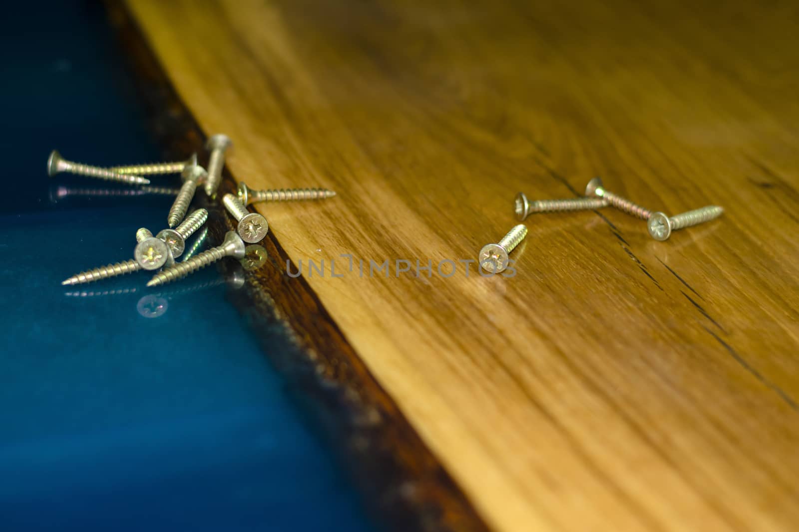 golden screws on the table made of wood and epoxy resin closeup by jk3030