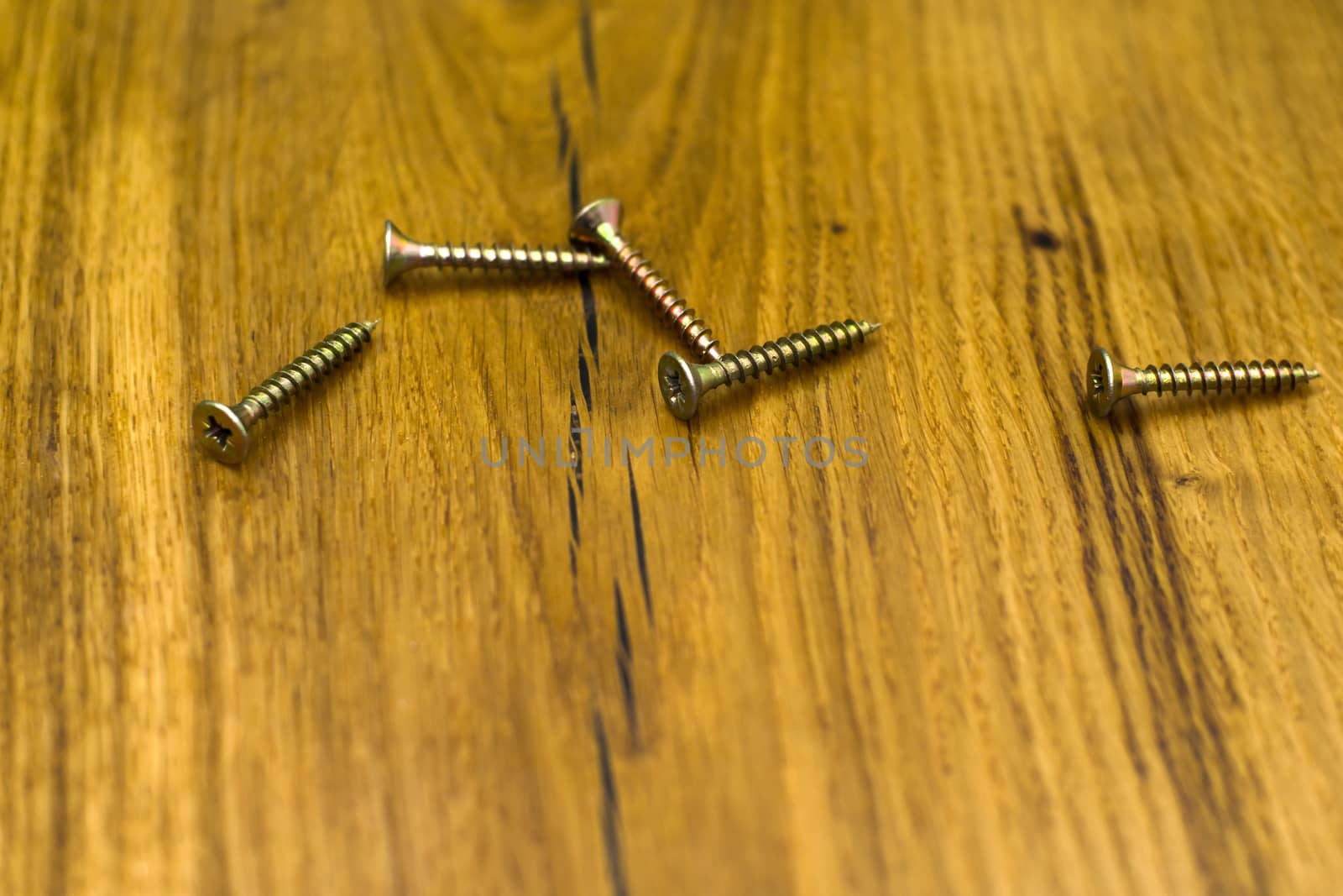 golden screws on the table made of wood closeup