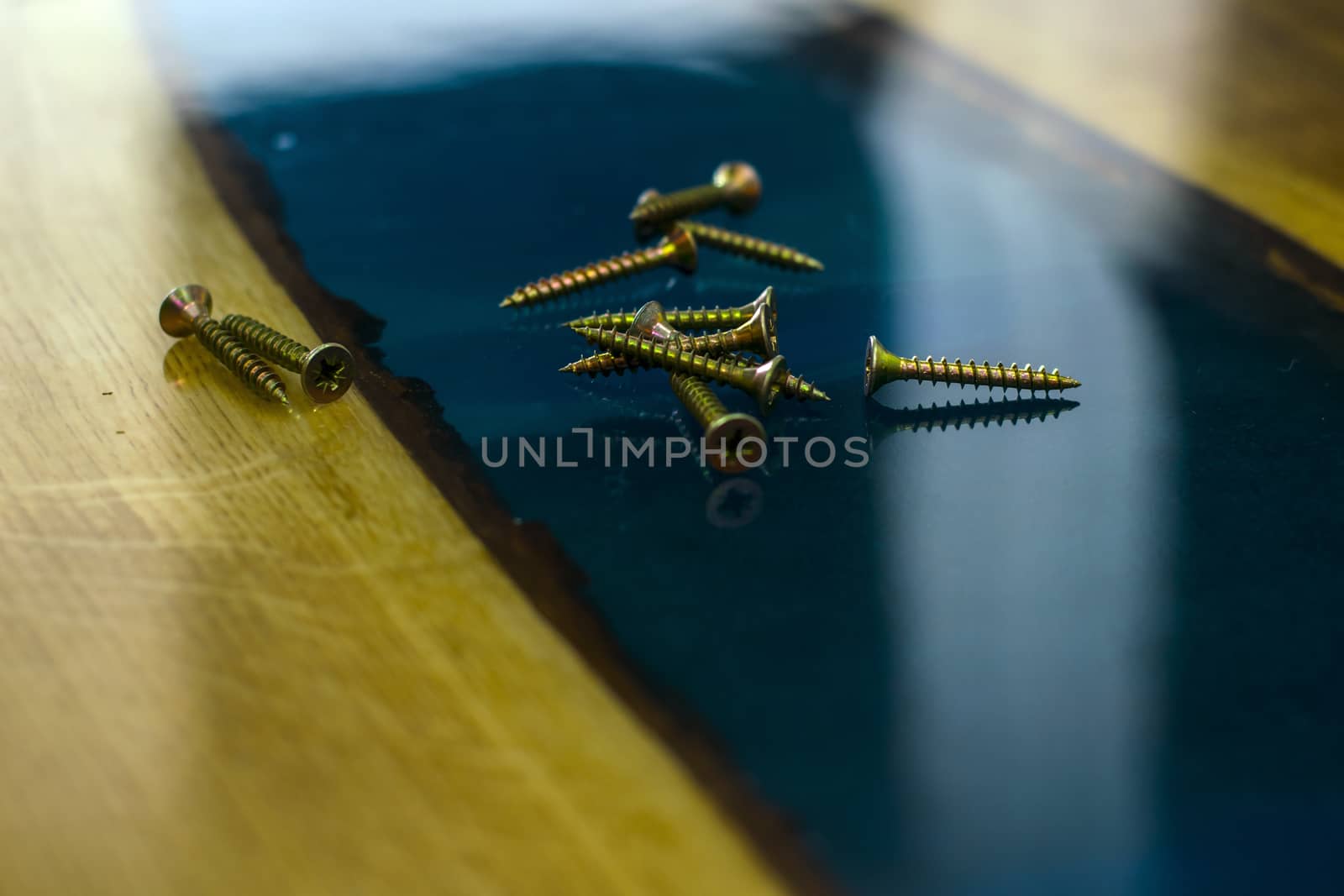 golden screws on the table made of wood and epoxy resin closeup