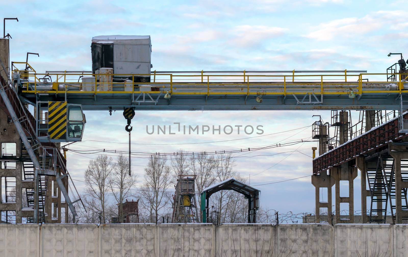 stationary crane in the protected area of the plant behind a concrete fence fence