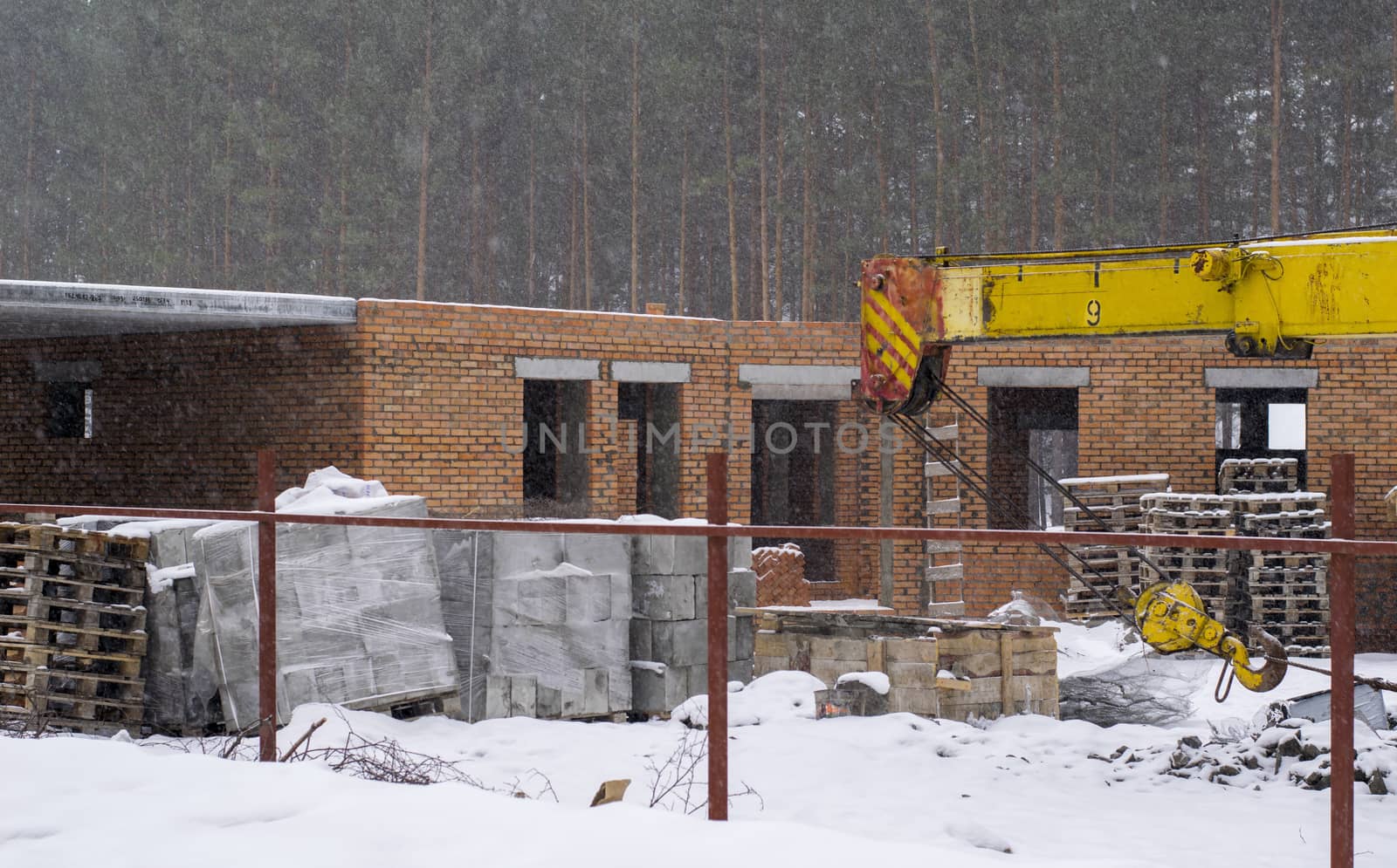 building materials and unfinished house in the winter and the crane jib