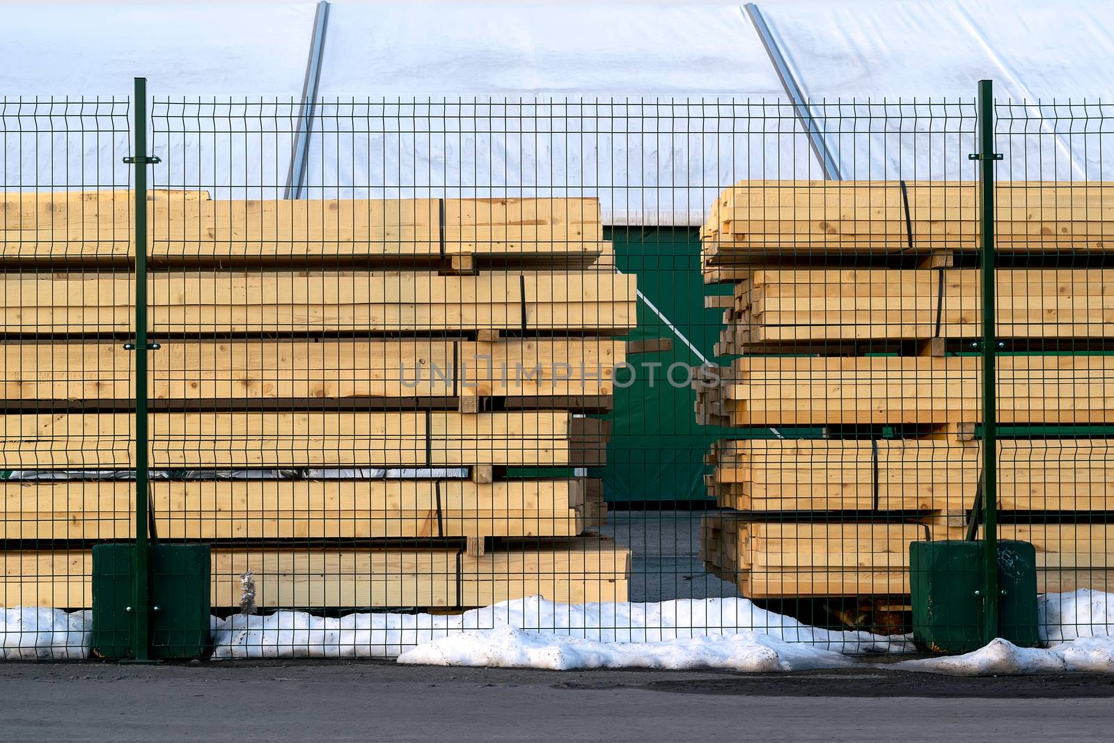 hewn, carved square logs. Lumber neatly stacked behind the fence by jk3030