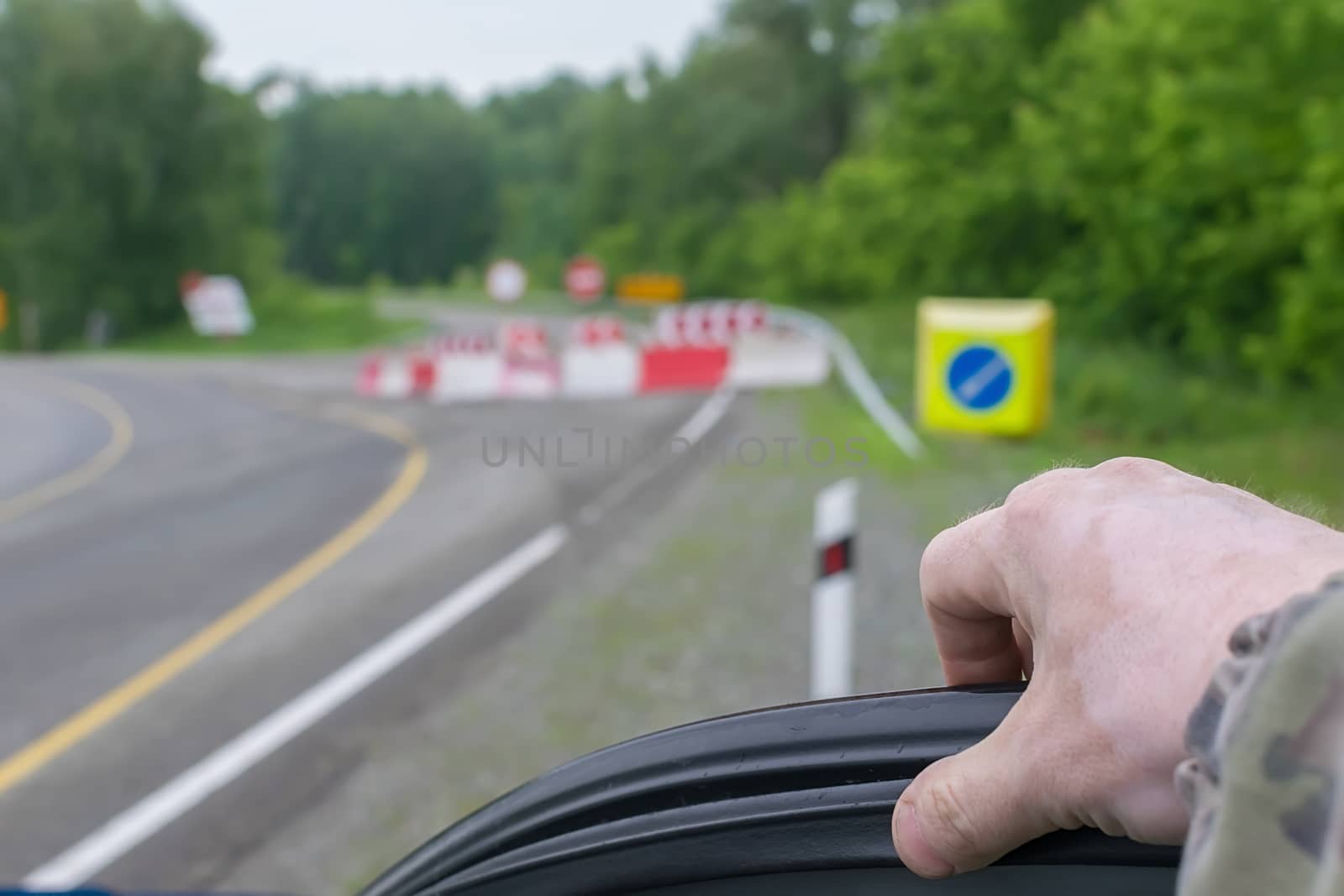 close up, the hand of a man getting out of a car against the background of a blocked road and detour signs