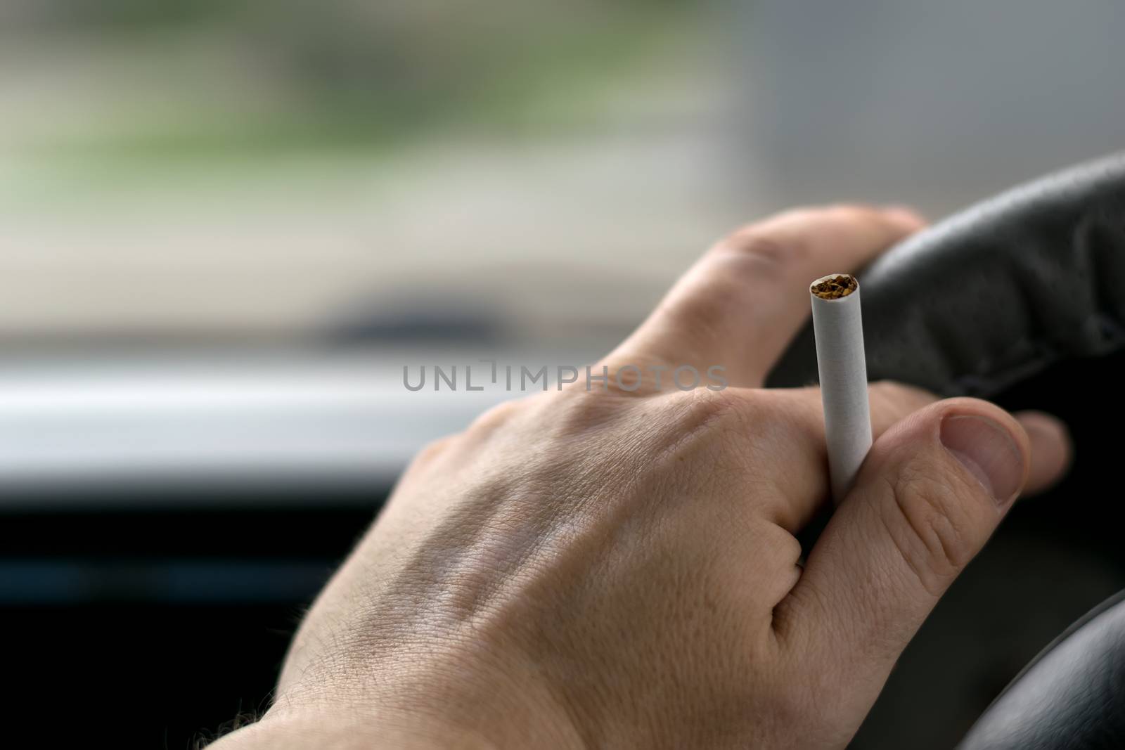 close-up, the hand of the driver of the car with skin disease "vitiligo" holds a cigarette