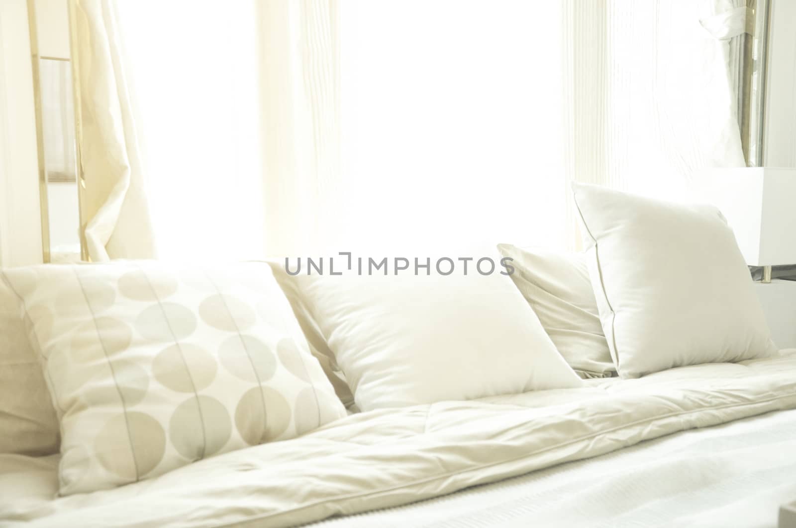 Bed maid-up with clean white pillows and bed sheets in luxury room. Close-up. Lens flair in sunlight.